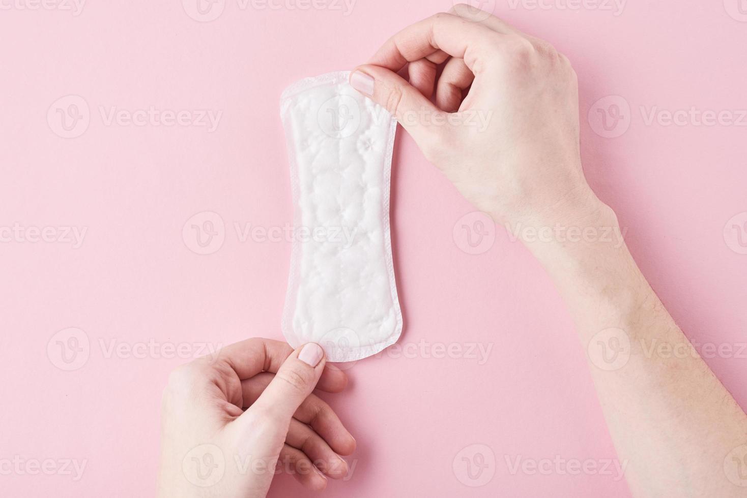 Woman hands hold sanitary pad on a pink background photo