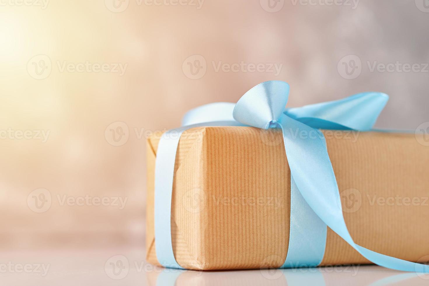 close up gift box in craft paper with blue ribbon on a gray background photo