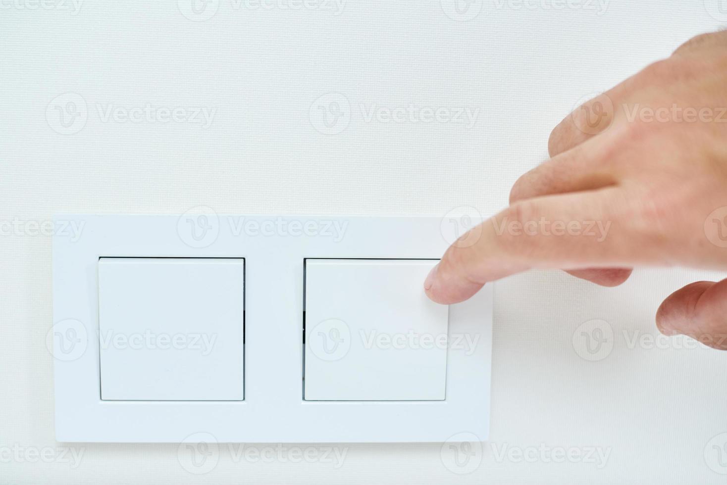 Hand is turning on or off on light switch, closeup photo