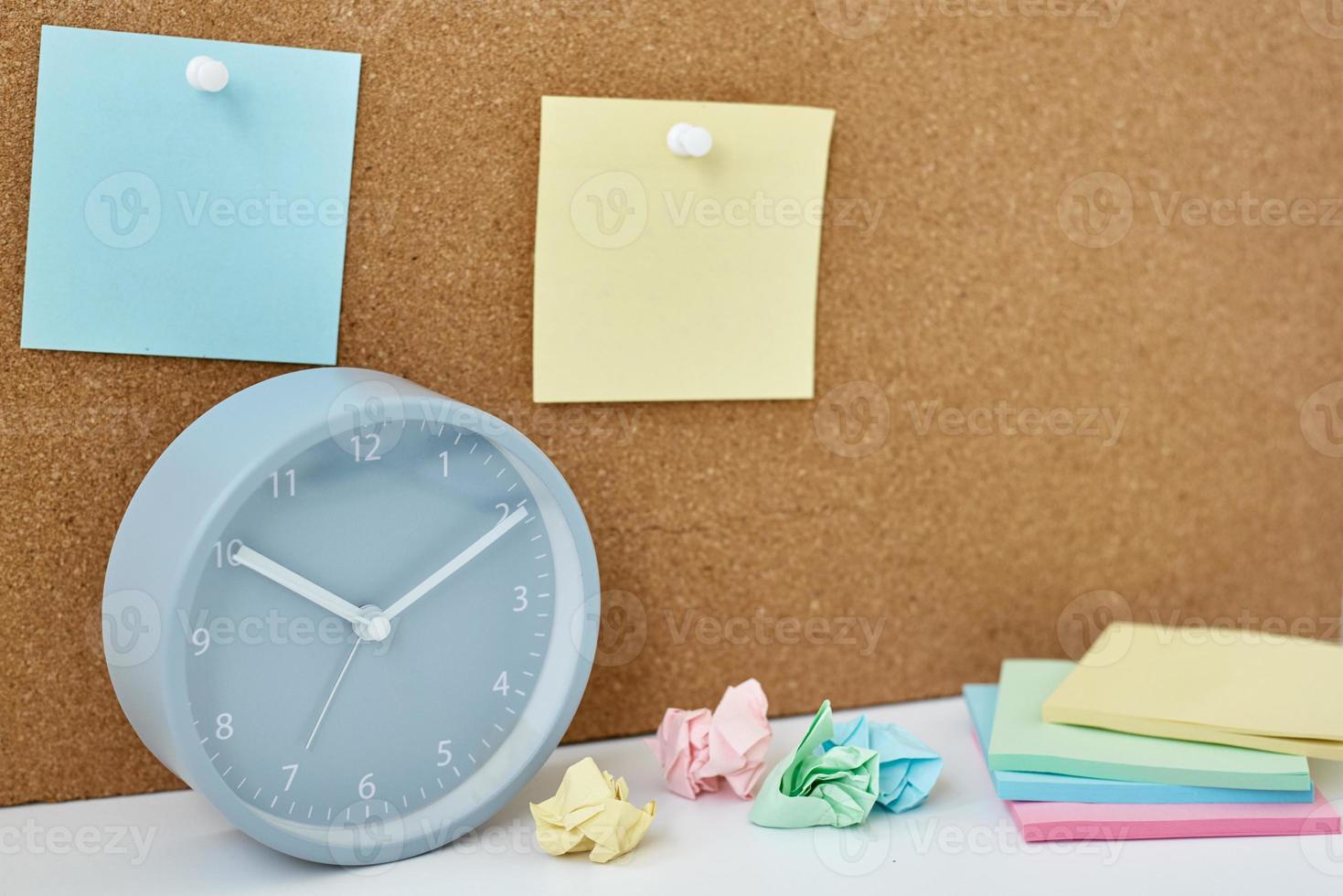 Sticky notes on a cork board and alarm clock in workplace office or home photo