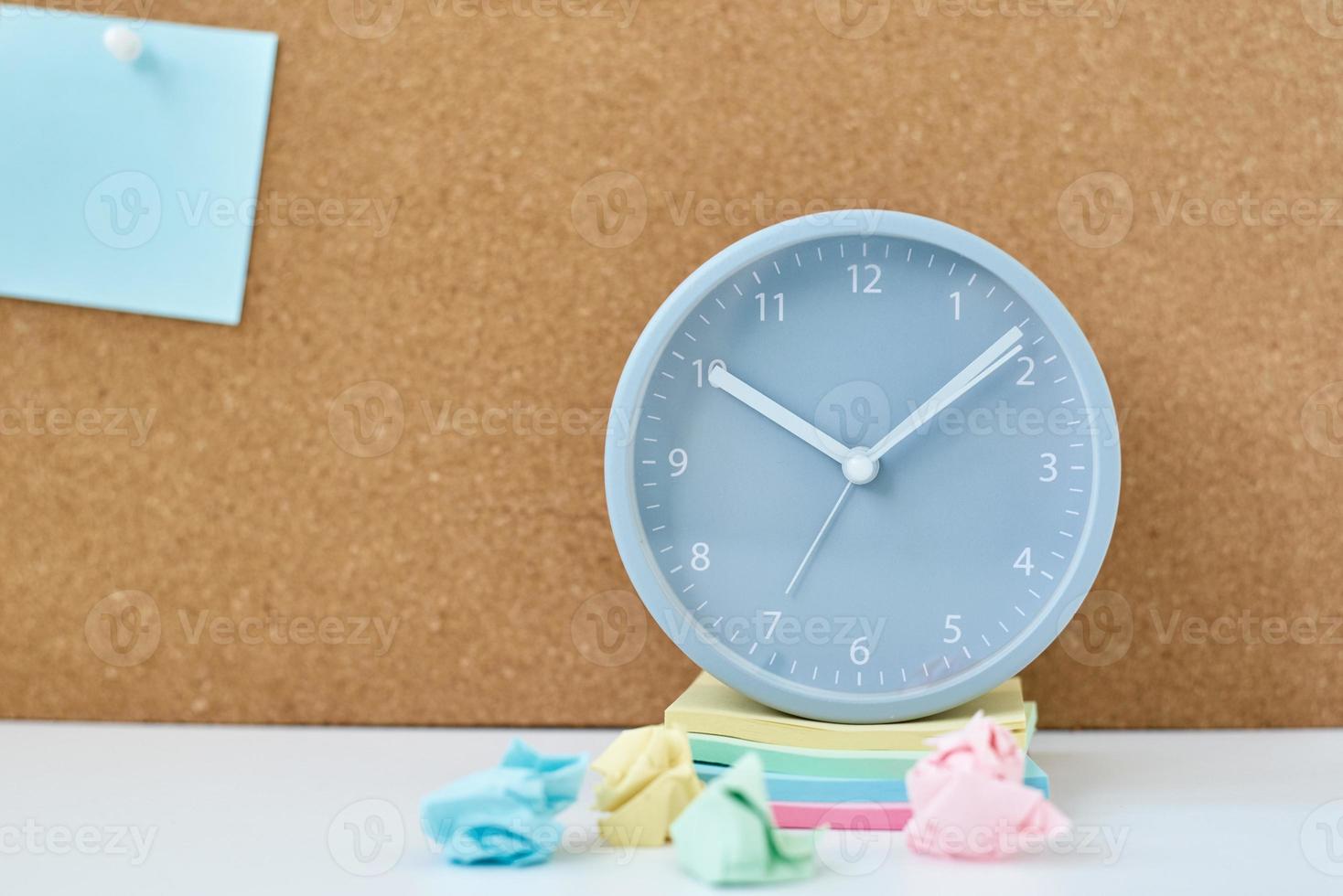 Sticky notes on a cork board and alarm clock in workplace office or home photo