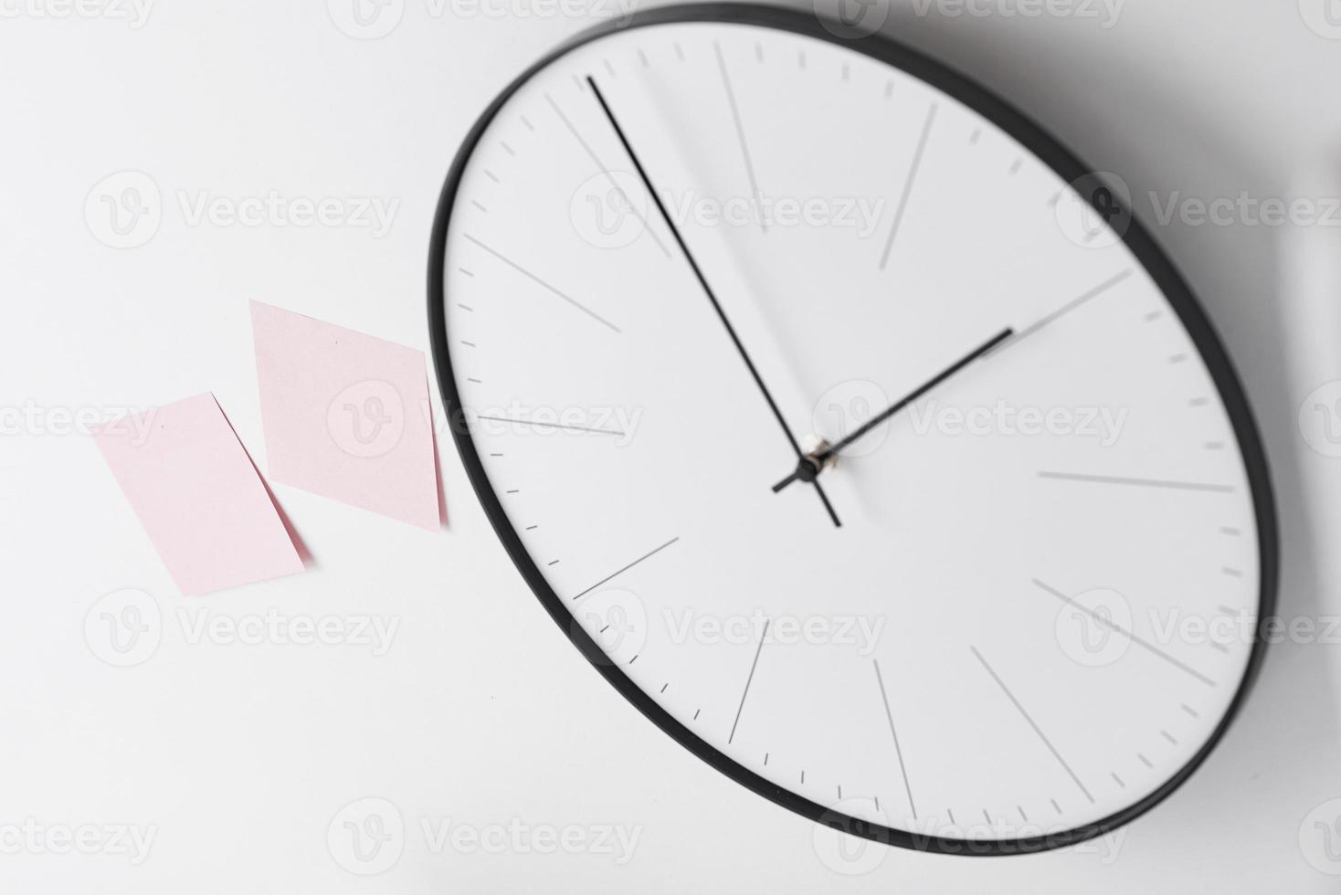 Round wall clock and pink stickers on white photo