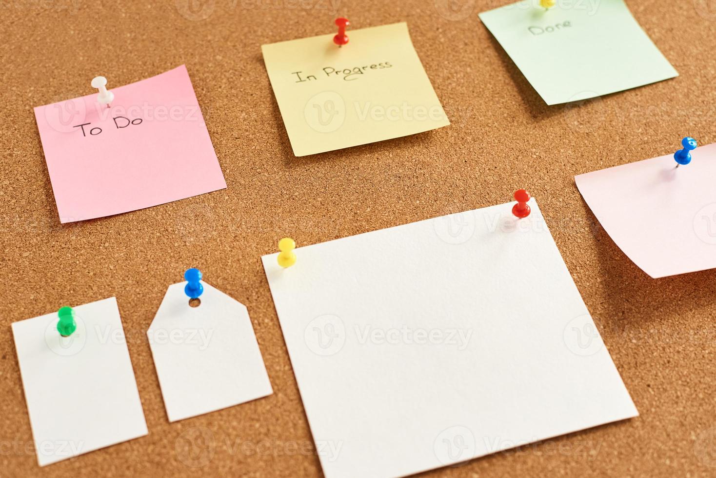 Colorful paper notes with words To do, In progress and Done pinned on a cork board photo