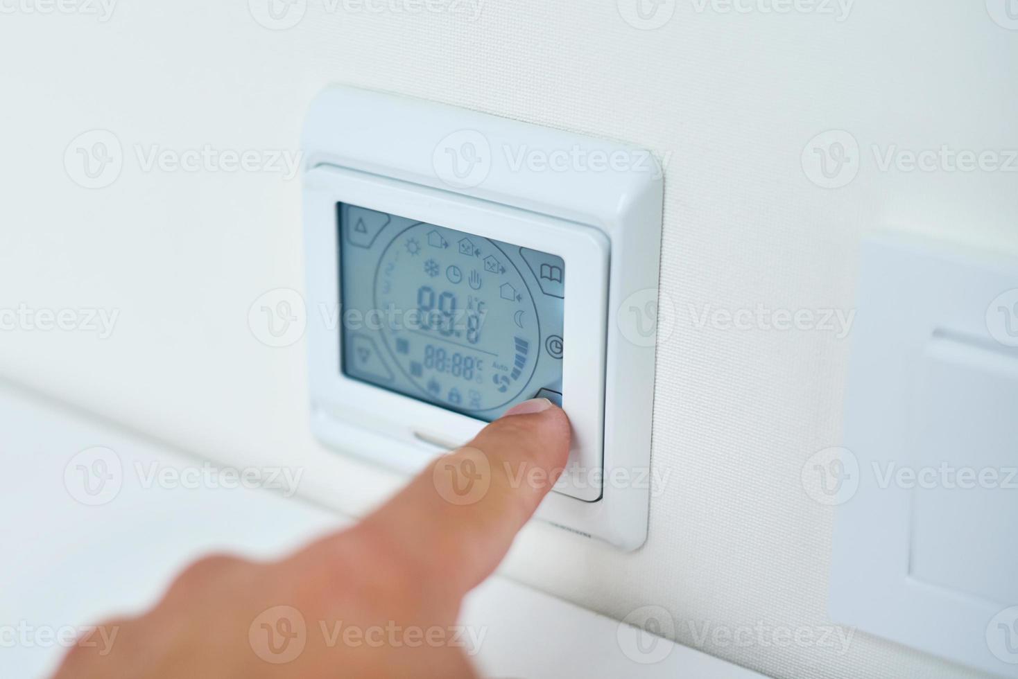 Men hand setting temperature on the underfloor heating control panel photo