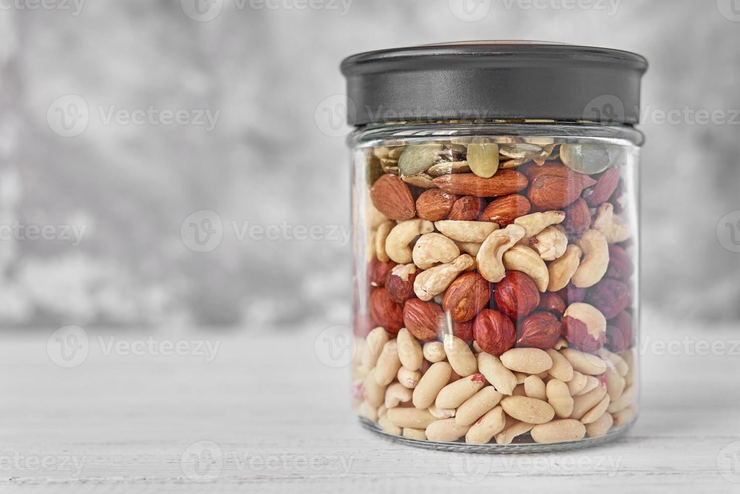 Different types of nuts and seeds in a glass jar close up photo