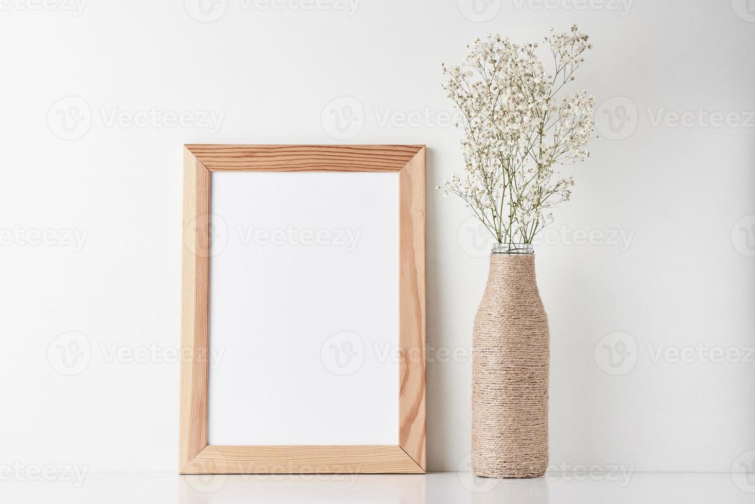 Workspace desk with empty frame and flower in vase photo
