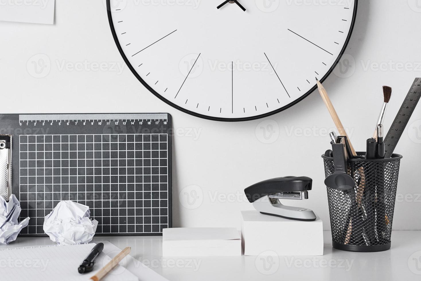 Office supplies and wall clock on white photo