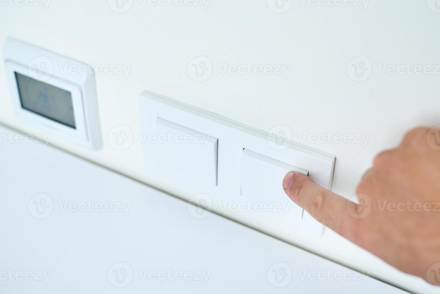 Hand is turning on or off on light switch, closeup photo