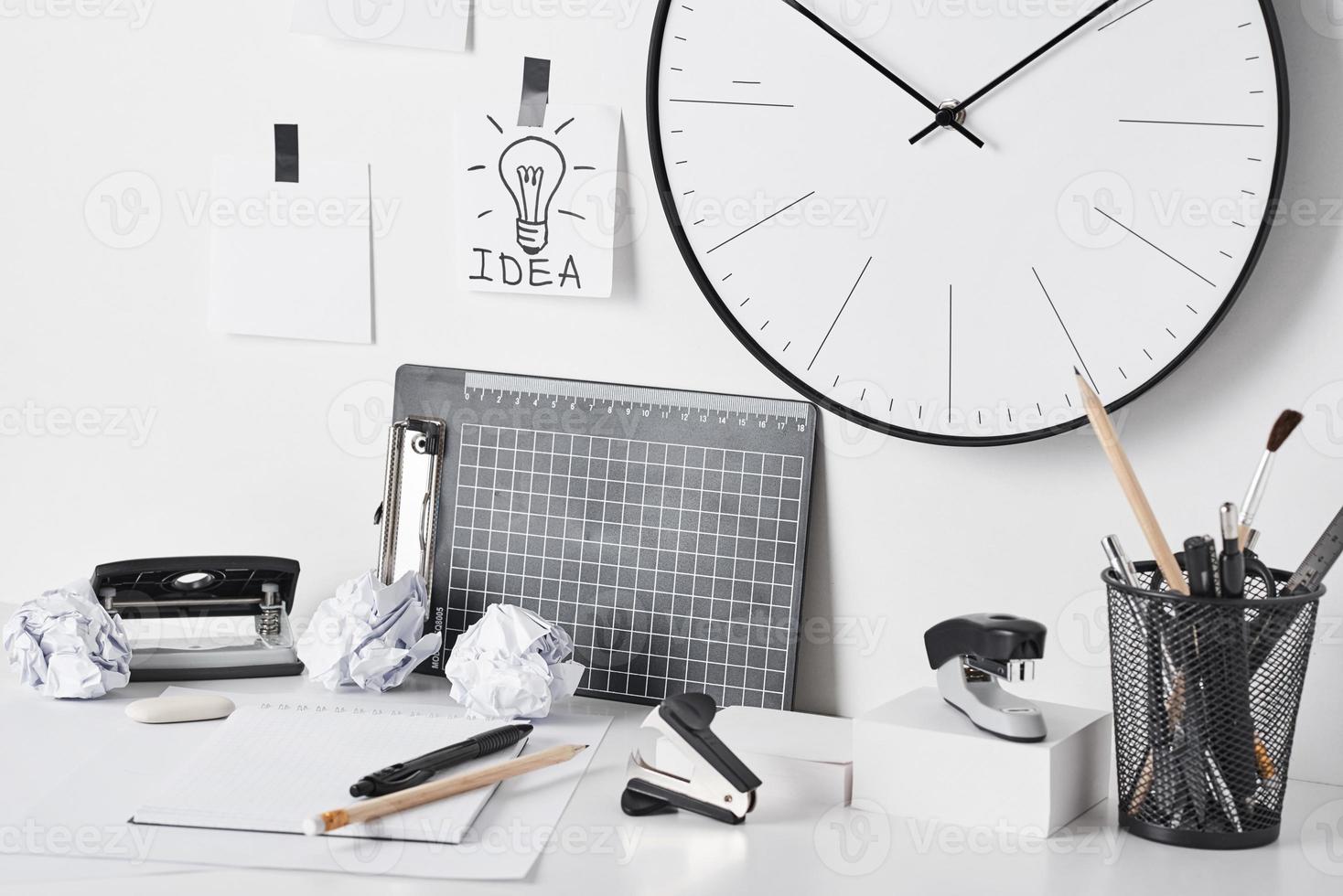 Office supplies and wall clock on white photo