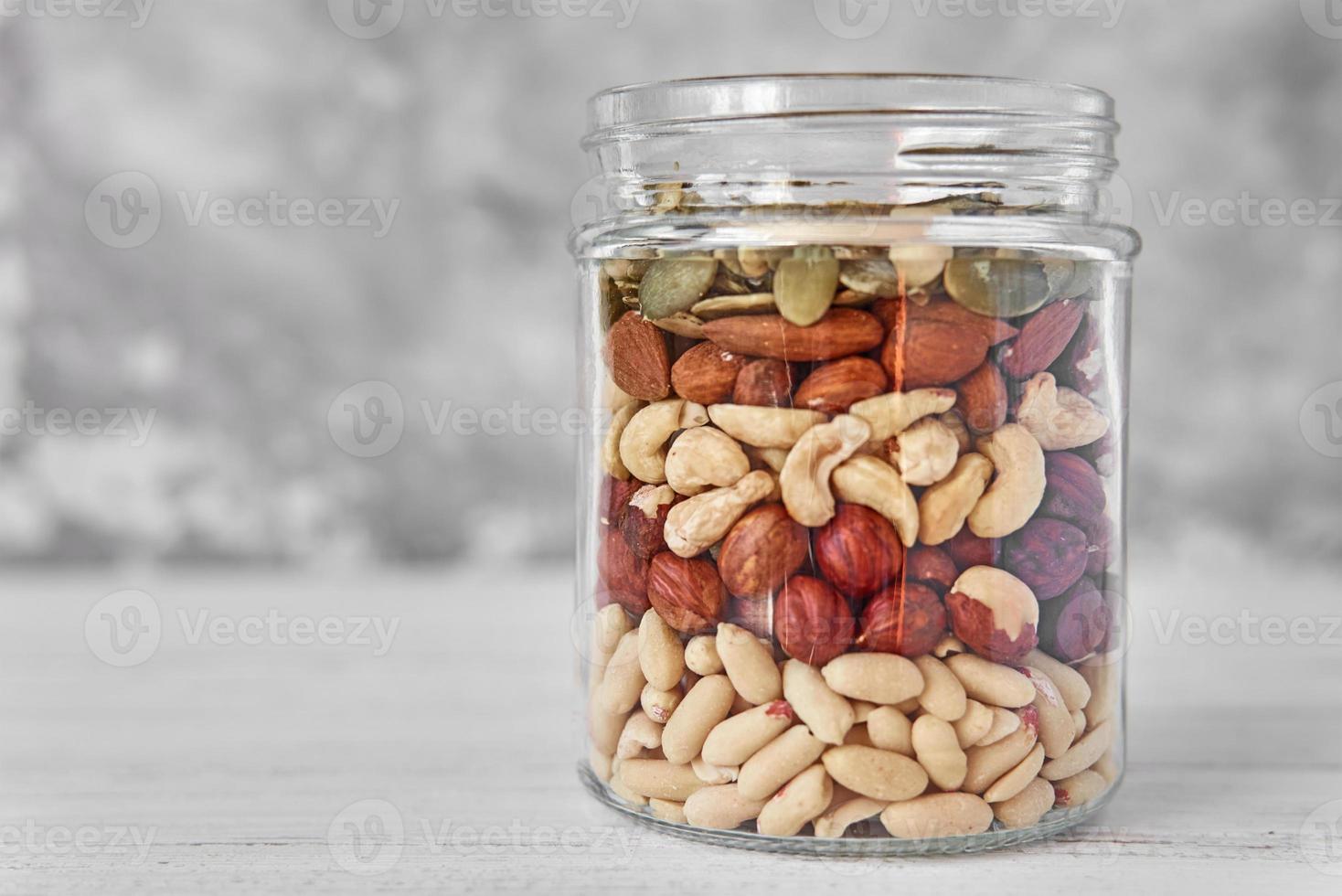 Layers of different types of nuts and seeds in a glass jar close up photo