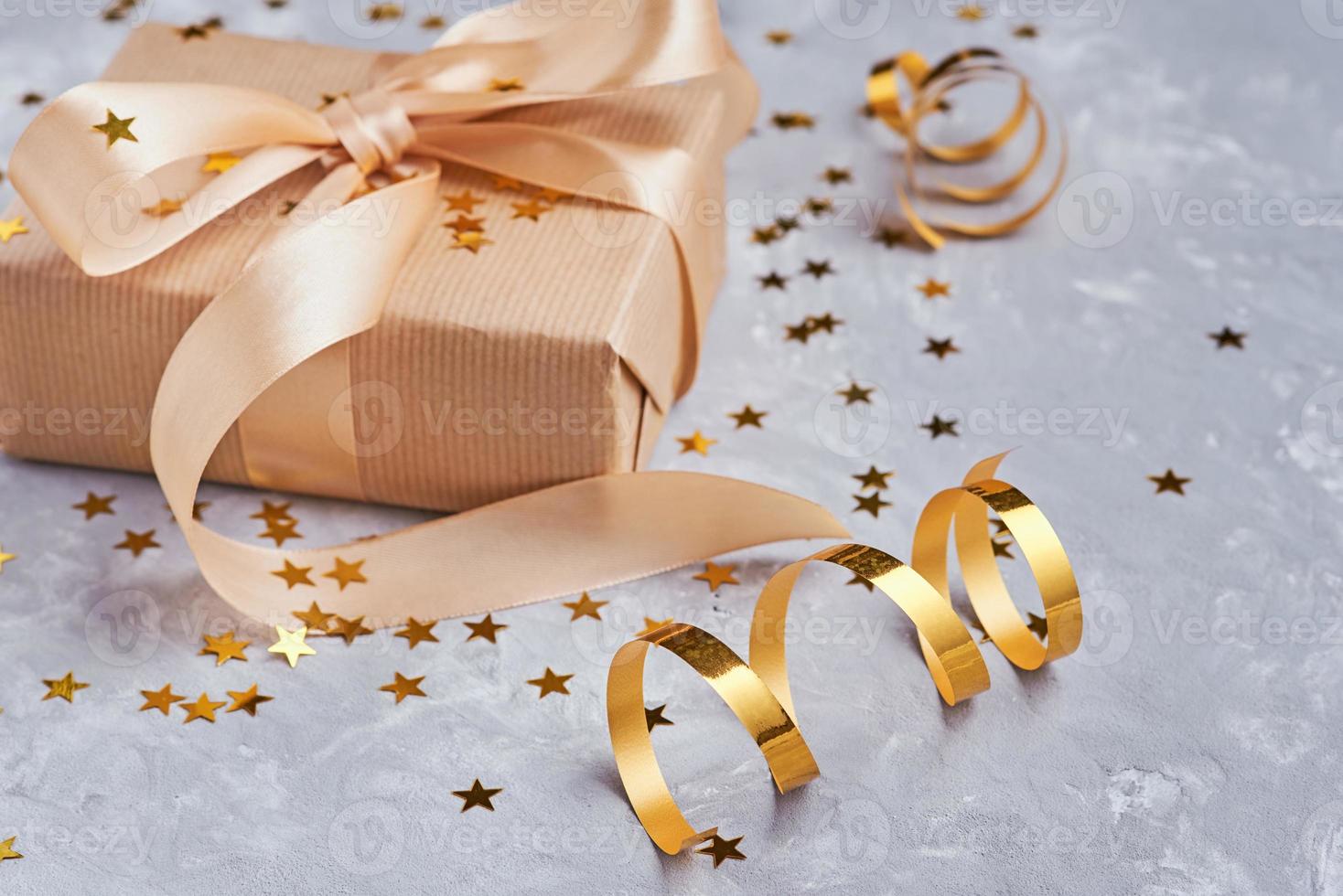 Gift box with golden bow and confetti, close up photo