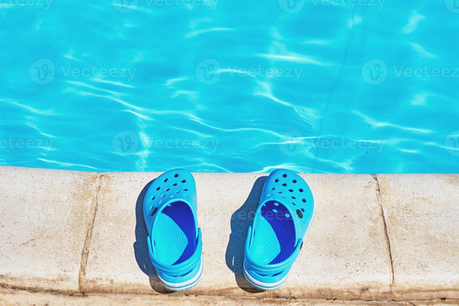 Blue flip flops near a swimming pool, close up photo