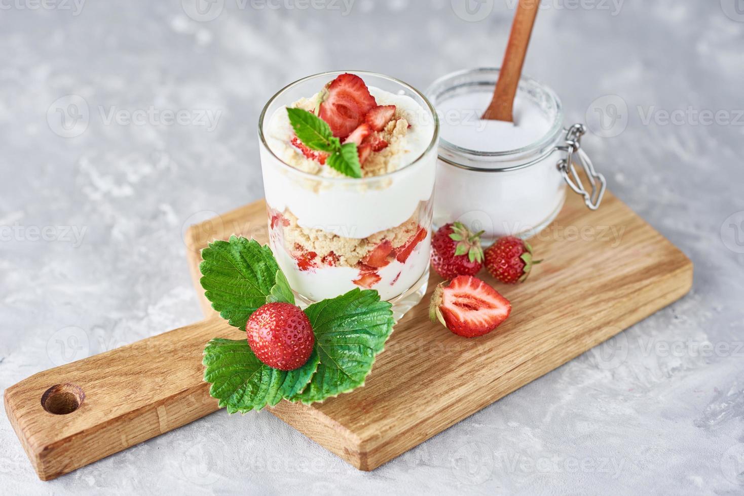 granola o yogur con fresa en vaso, bayas frescas y tarro con azúcar foto
