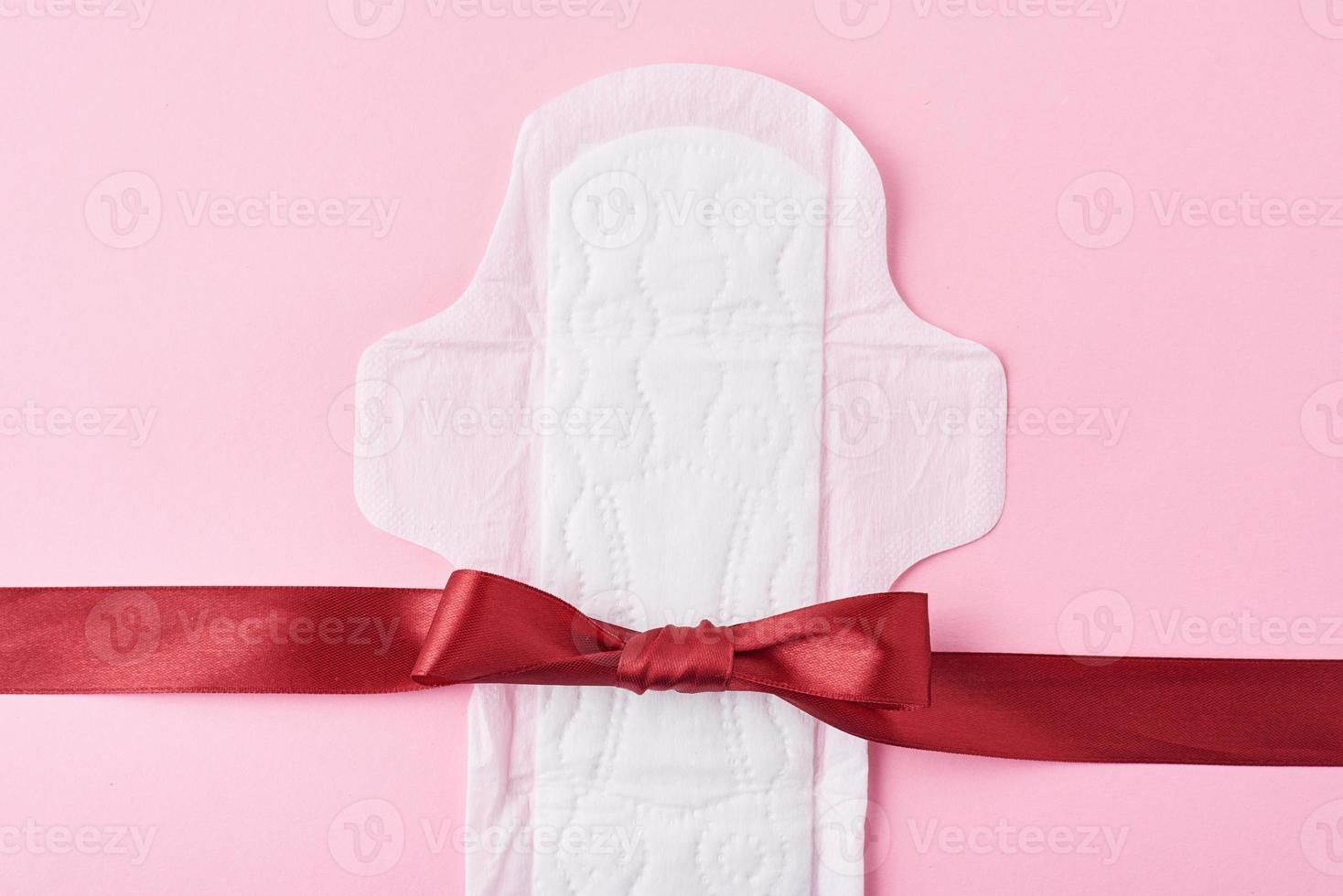 Sanitary pad and red ribbon on a pink background photo