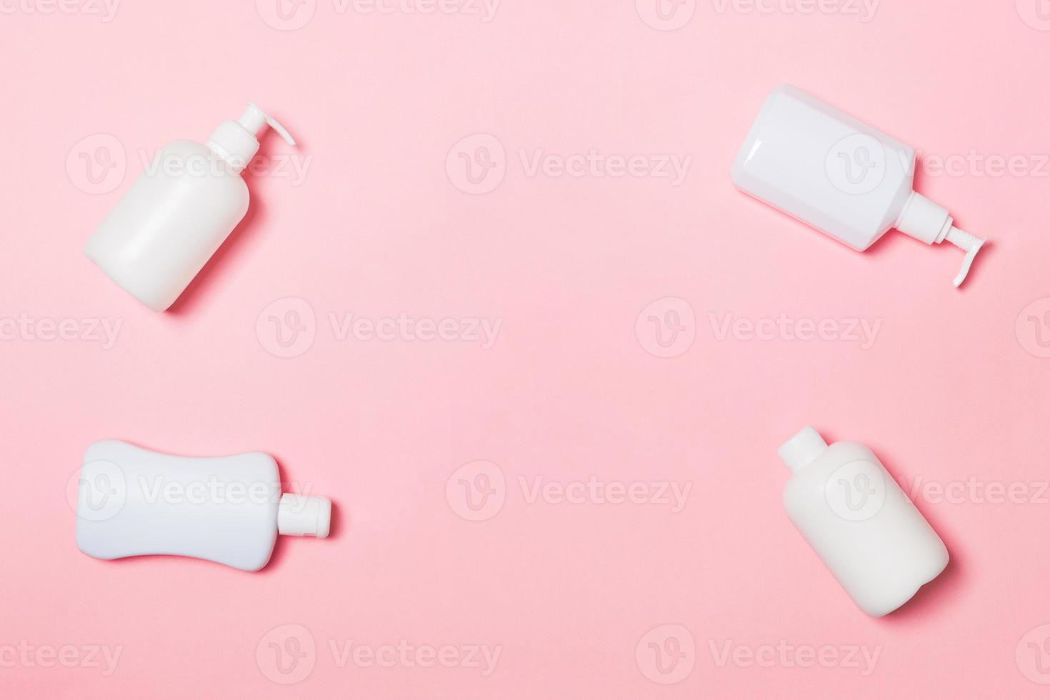 conjunto de recipientes cosméticos blancos aislados sobre fondo rosa, vista superior con espacio de copia. grupo de envases de botellas de plástico para el cuidado del cuerpo con espacio vacío para su diseño foto