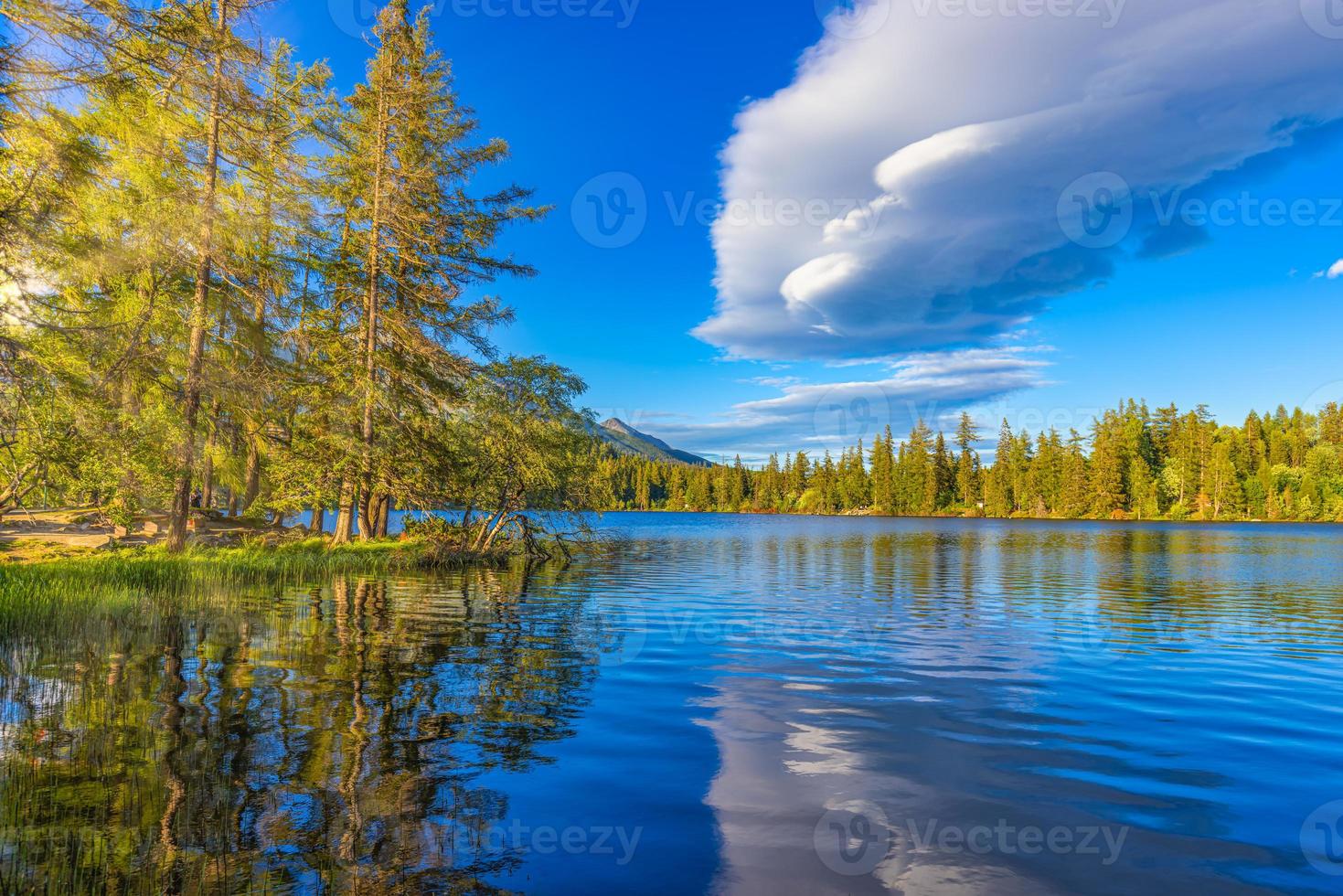Beautiful early autumn scene of High Tatra lake. Colorful morning view of mountains sunlight, pine forest trees, idyllic sky reflection. Amazing nature landscape. Hiking adventure, beauty outdoors photo