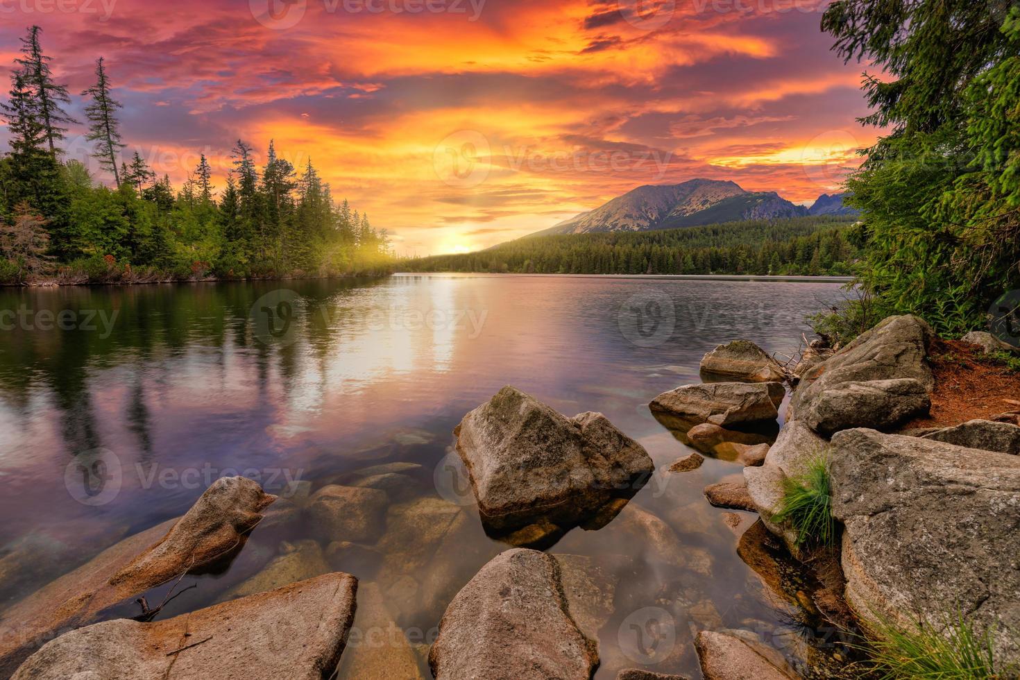 Impresionante paisaje natural. hermosa escena con picos de alta montaña tatra, piedras en el lago de montaña, agua tranquila del lago, reflejo, cielo colorido de la puesta de sol. increíble fondo de naturaleza. aventura de otoño senderismo foto