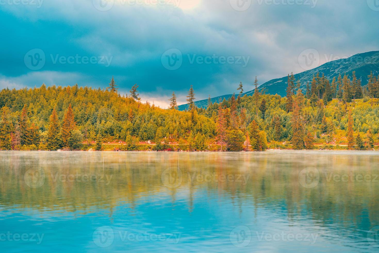 paisaje de puesta de sol de otoño con tranquilo lago de montaña. naturaleza tranquila en temporada de otoño. amanecer de lago brumoso con follaje otoñal y montañas, cielo de nubes increíbles. fantasía naturaleza follaje foto