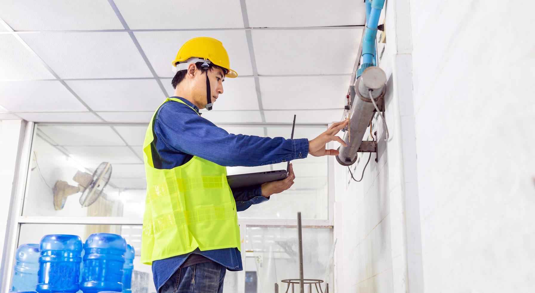 engineer working in drink water factory using a tablet computer to check and repair boiler water to the water system  in factory photo