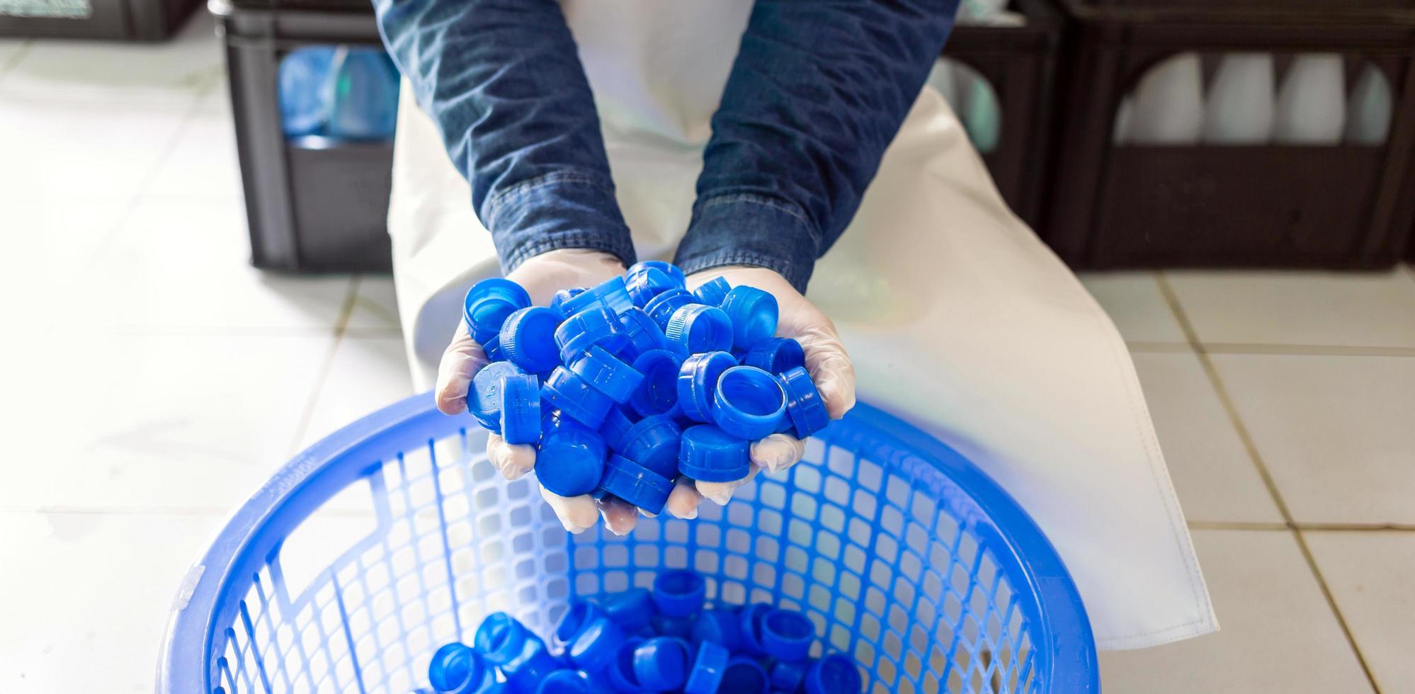 Blue plastic water bottle cap in hand worker or quality inspector in workwear in drink water factory.drinking water business photo