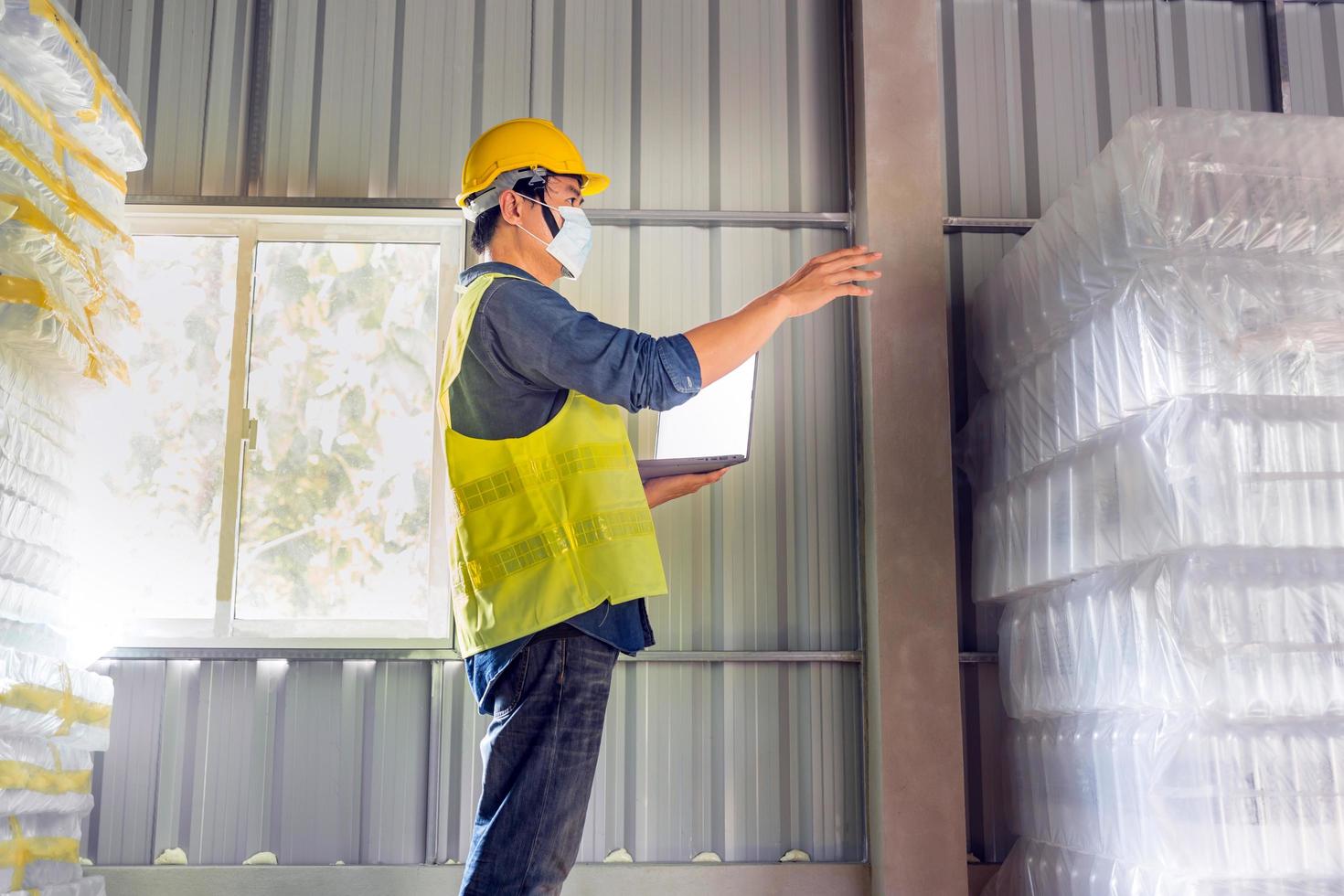 Young man worker and quality inspector in a factory checking number of white plastic bottles in the warehouse photo