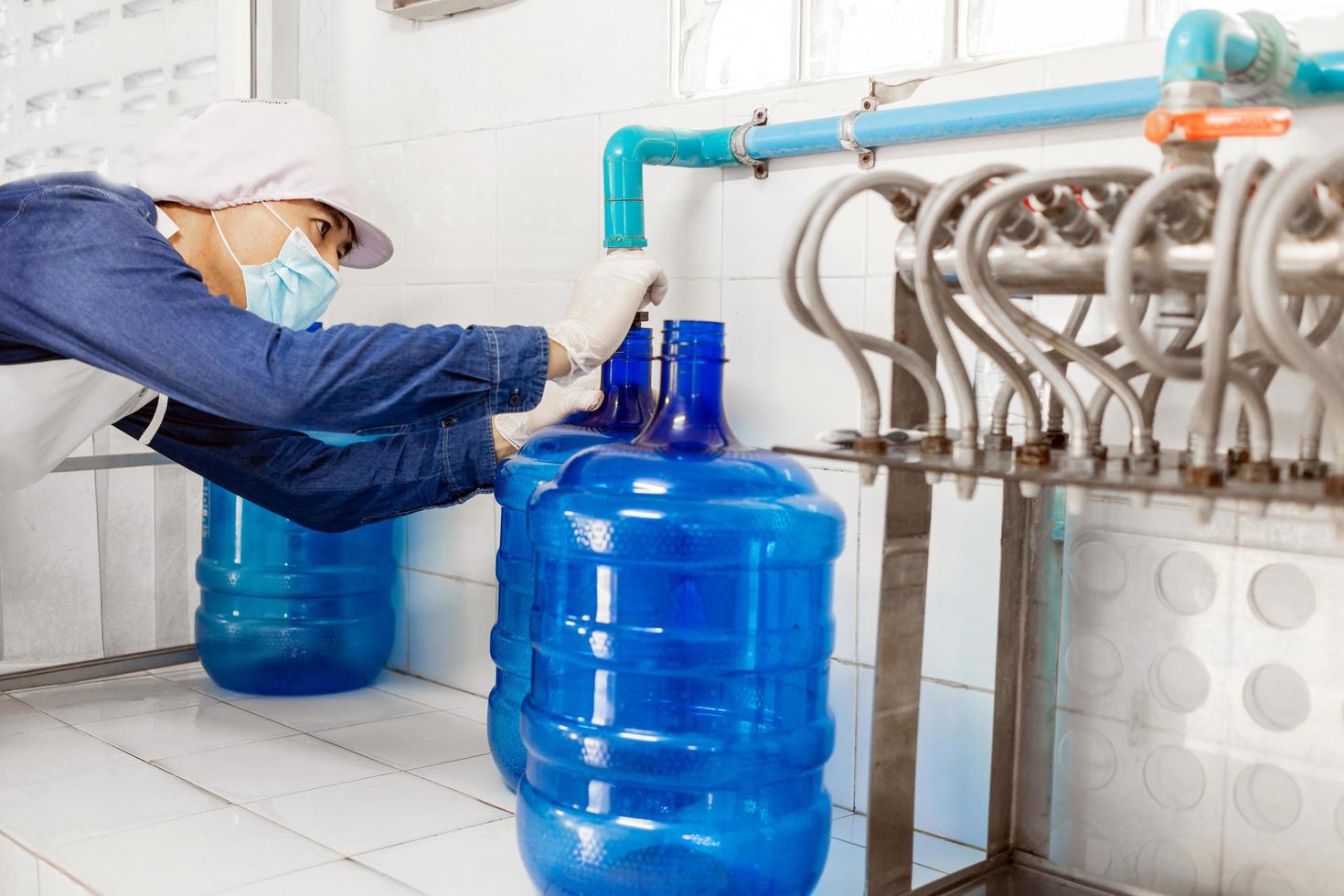 man worker in workwear and with a protective mask on his face working produces drinking water in a clean drinking water factory. clean drinking water production line photo