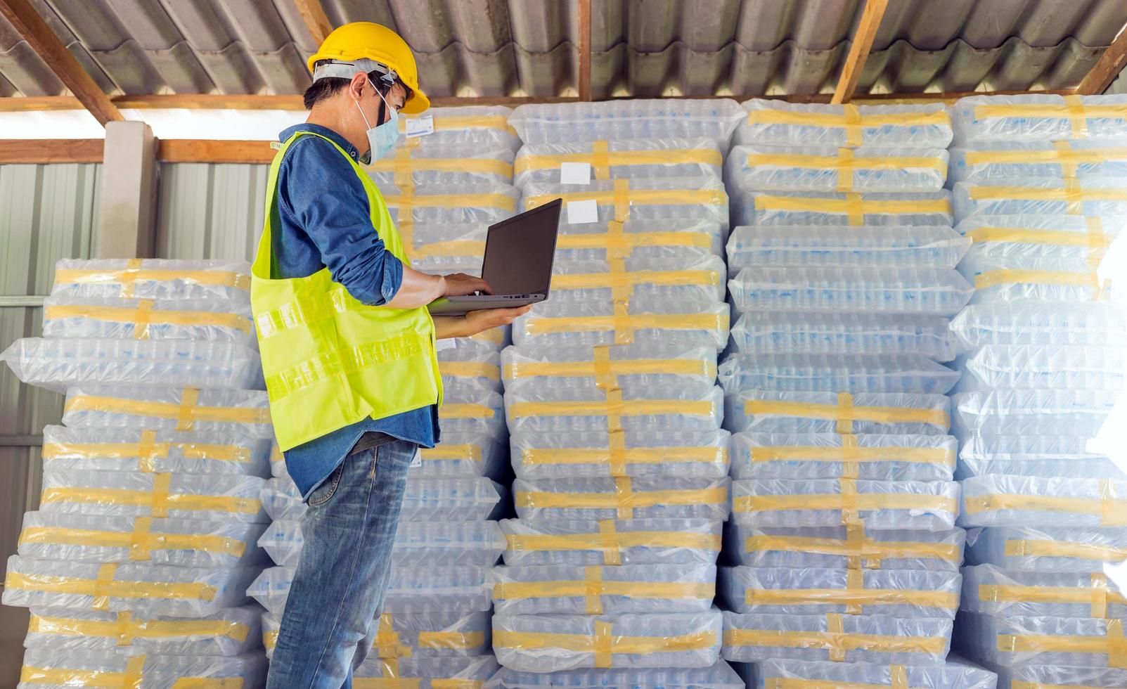 joven trabajador e inspector de calidad en una fábrica comprobando el número de botellas de plástico blancas en el almacén foto