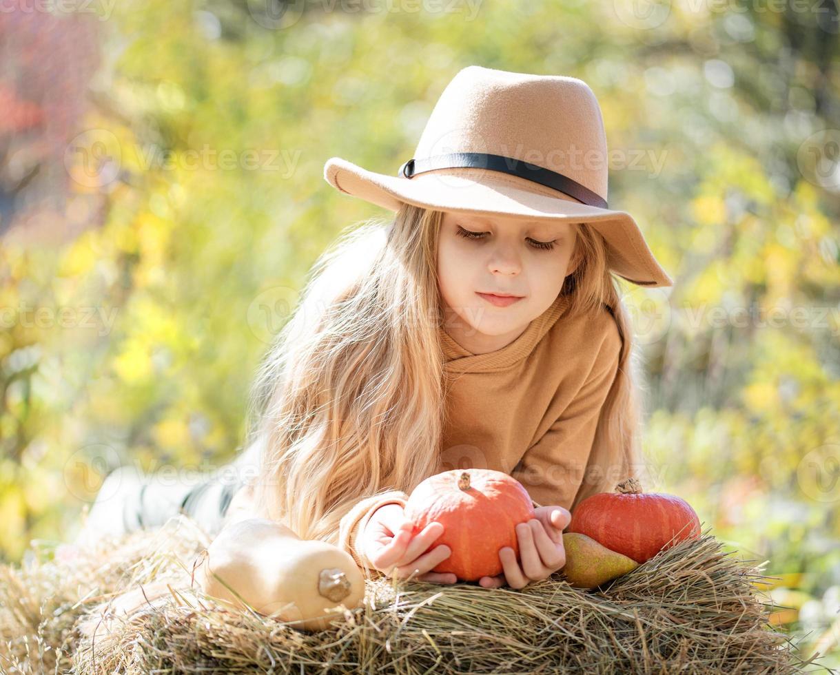 niña en el heno con calabazas foto