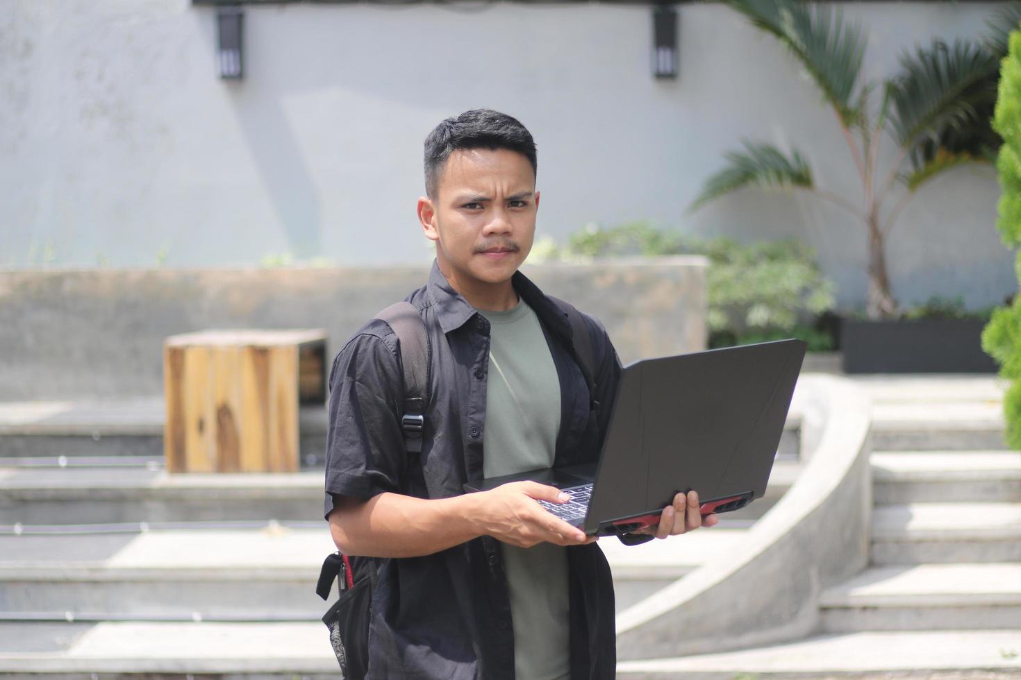 Attractive young Asian man using laptop in co-working space with happy face photo