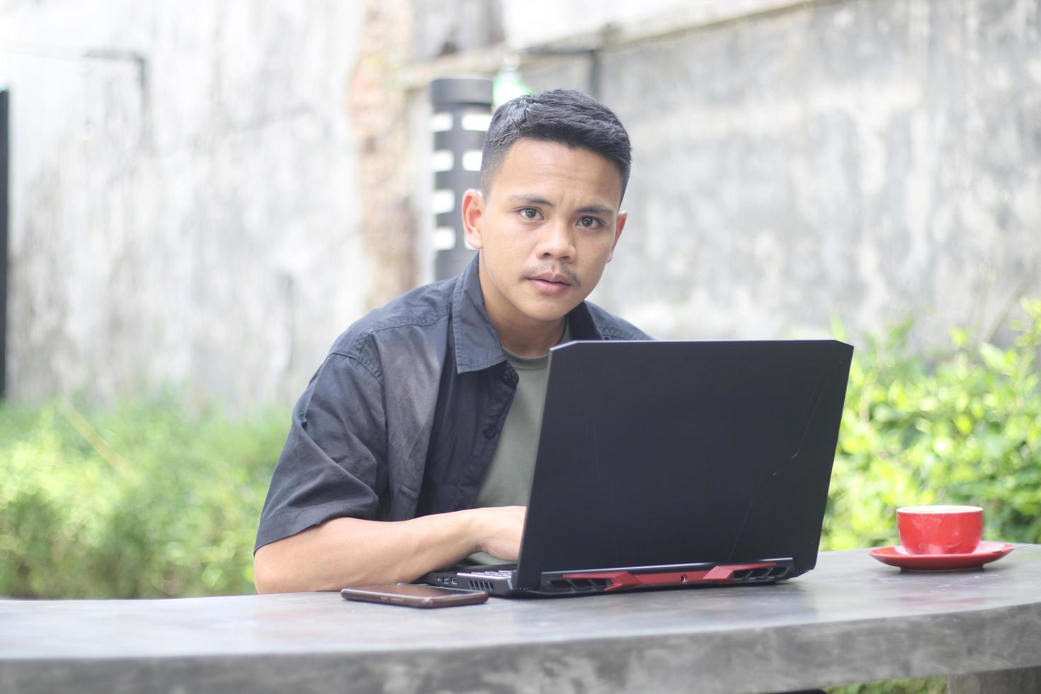 Attractive young Asian man using laptop in co-working space with happy face photo