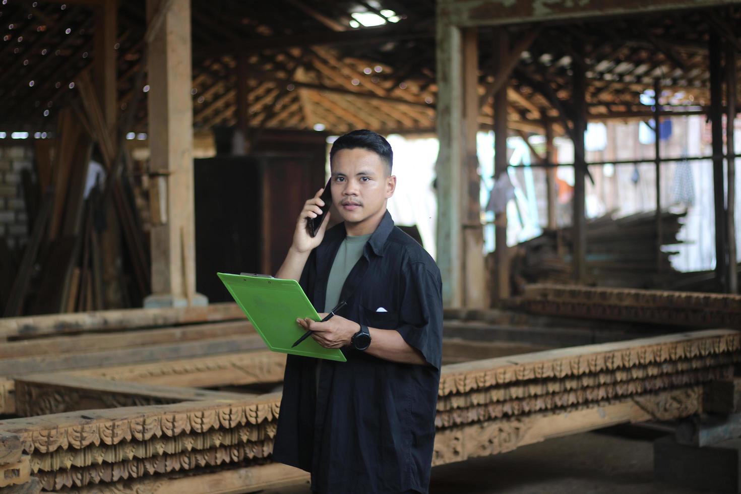 ASIAN YOUNG MAN BOSS OF WOOD COMPANY CALLING HER FRIEND AND CHECKING QUALITY photo