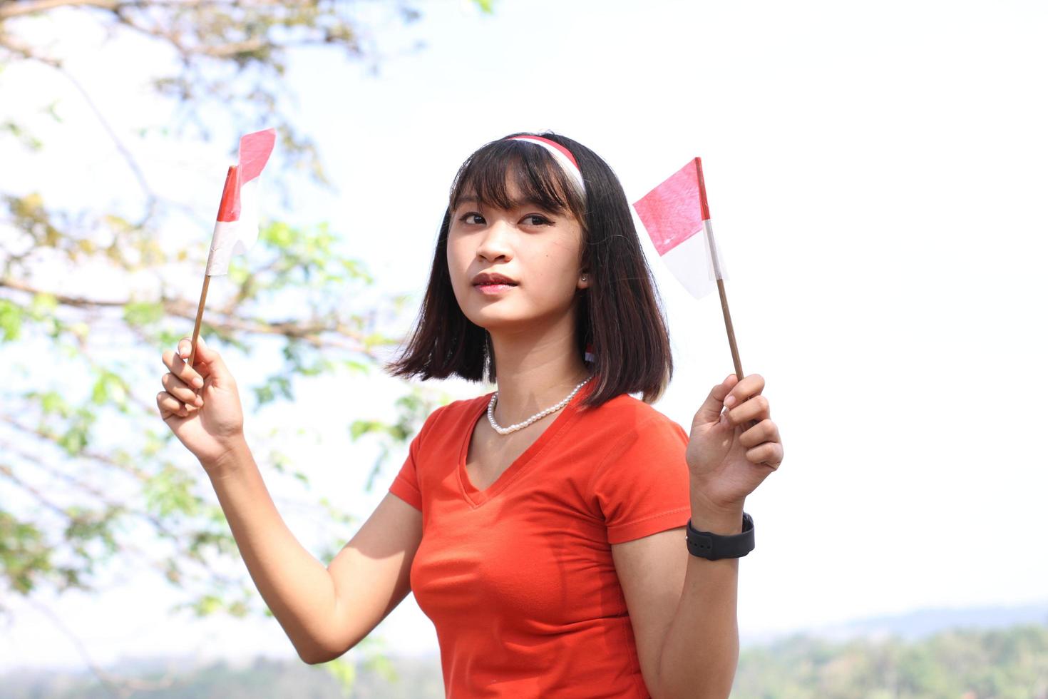 beautiful young asian woman carrying the indonesian flag with a cheerful face photo