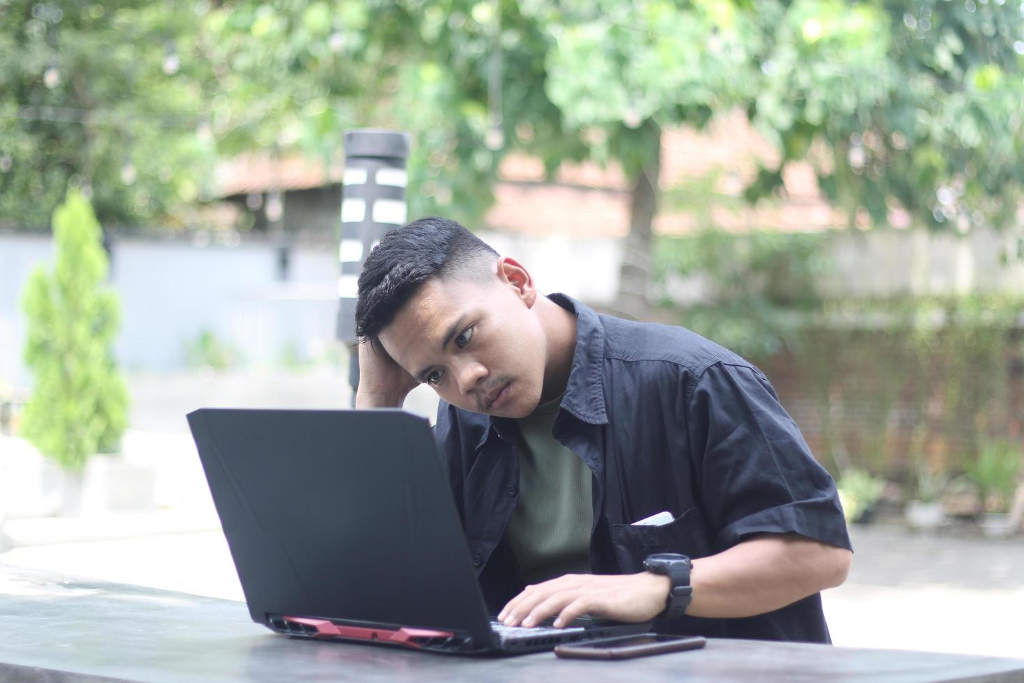 Attractive young Asian man using laptop in co-working space with happy face photo