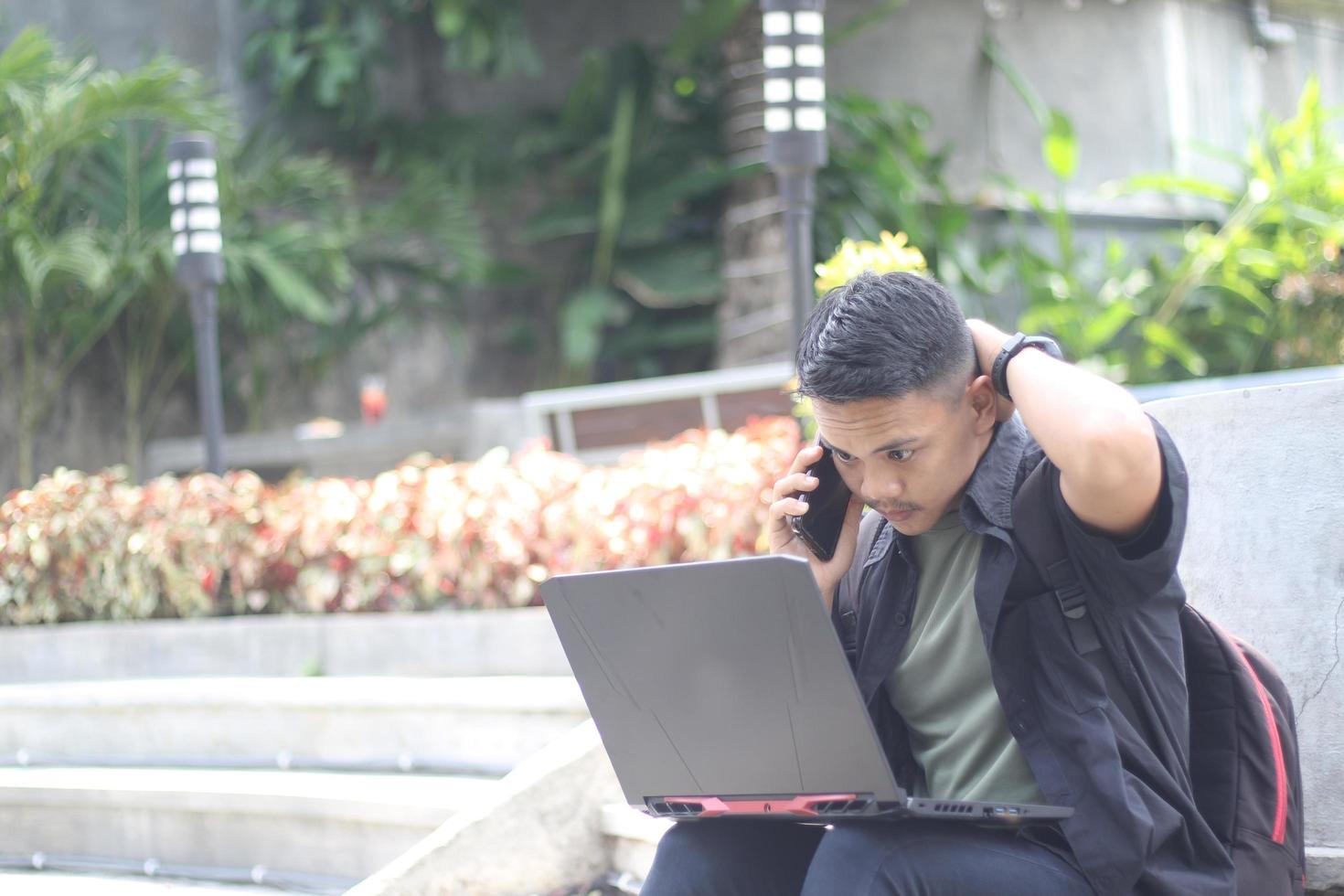 Attractive young Asian man using laptop confused in co-working space with unhappy face photo