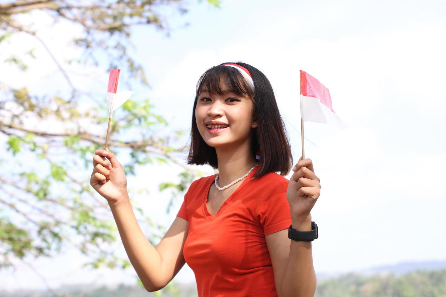 beautiful young asian woman carrying the indonesian flag with a cheerful face photo