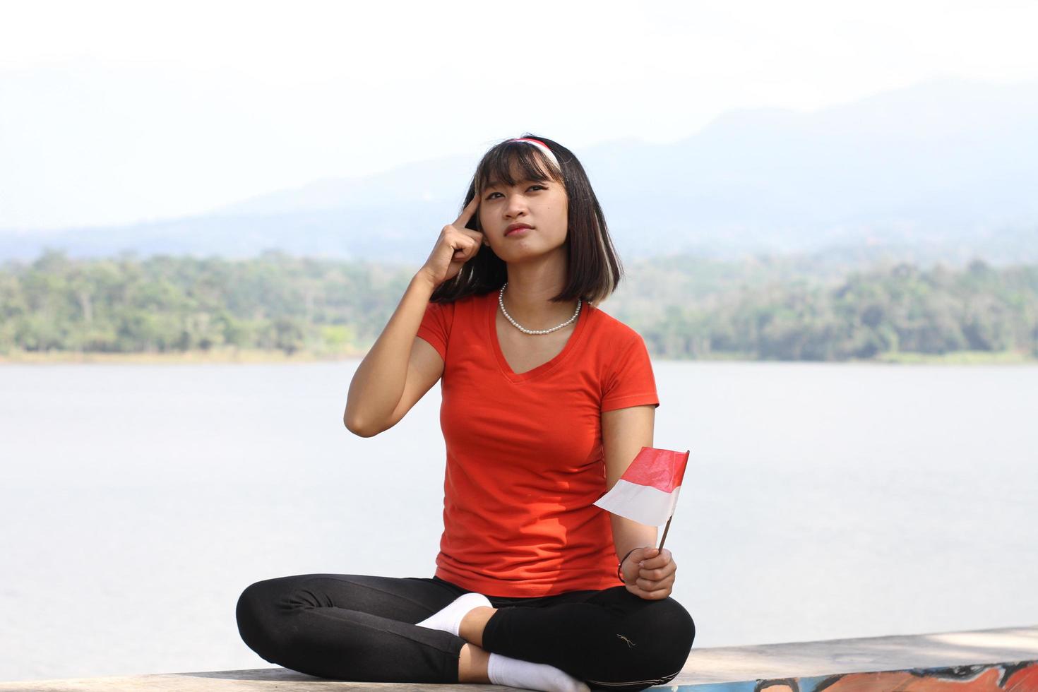 bella joven asiática que lleva la bandera indonesia con una cara alegre foto