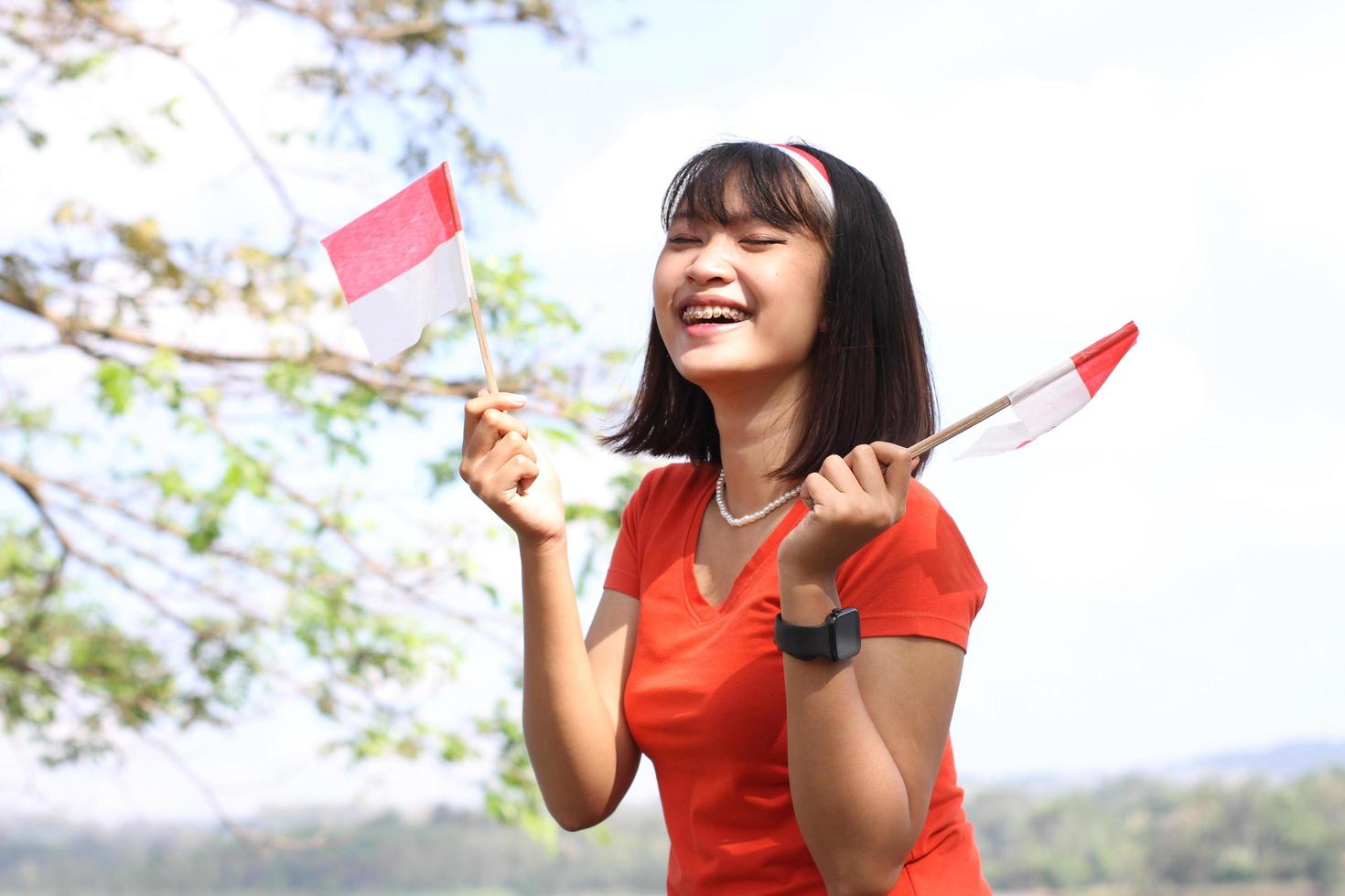 beautiful young asian woman carrying the indonesian flag with a cheerful face photo