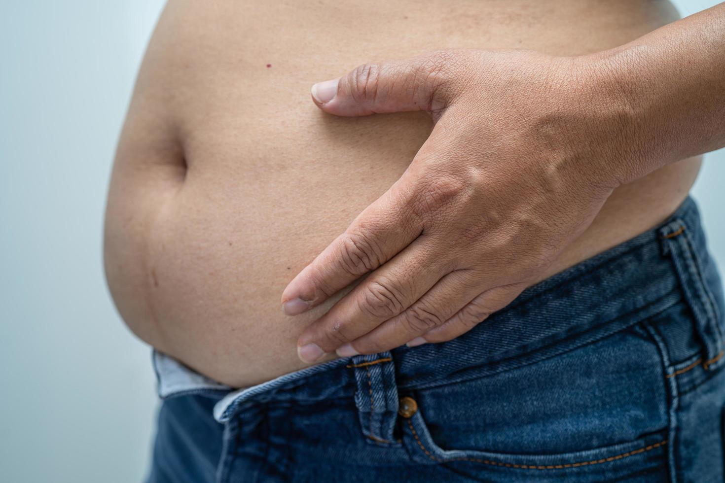 mujer asiática con sobrepeso muestra el vientre gordo en la oficina. foto