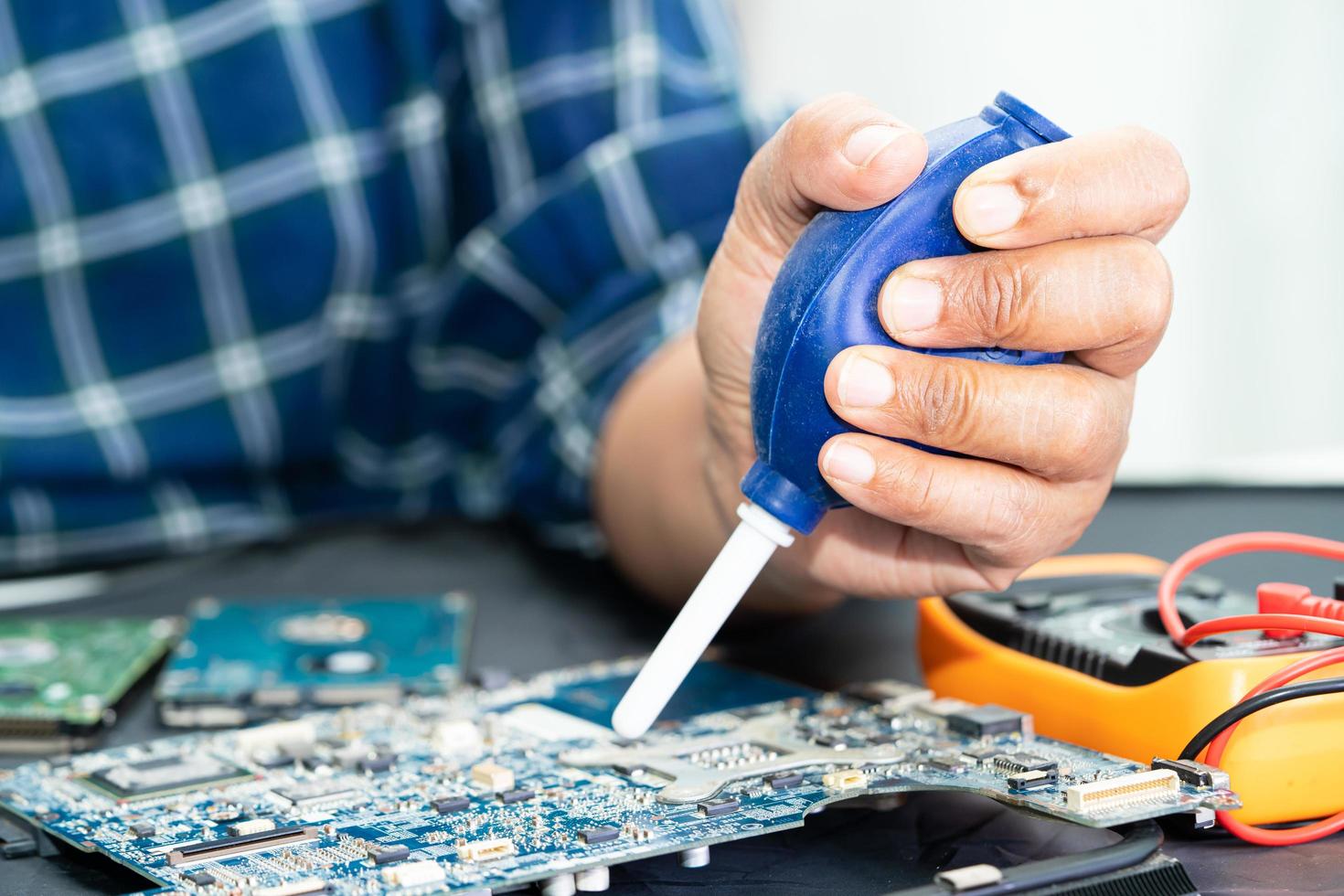 el técnico usa una bola de aire para limpiar el polvo en la computadora de la placa de circuito. actualización de reparación y tecnología de mantenimiento. foto