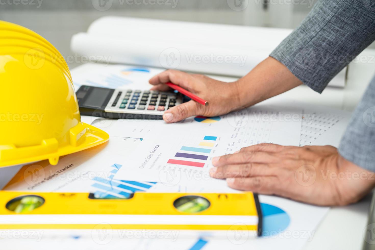 Asian engineer with architectural house plan project blueprint, graph and yellow helmet and engineering construction tools. photo