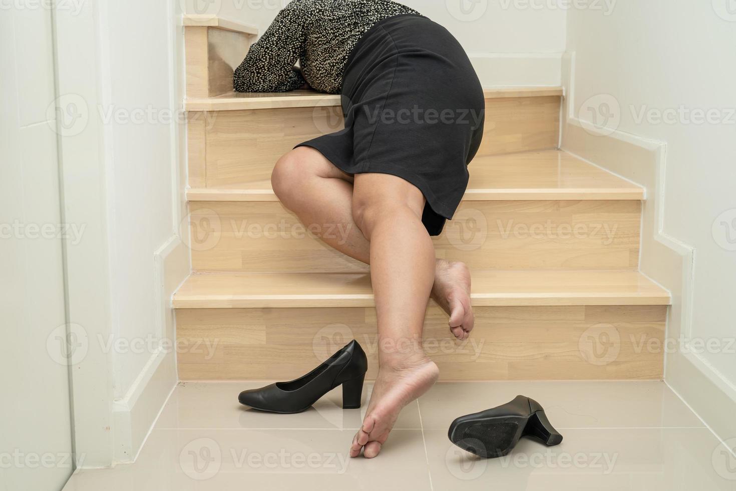 Asian business woman wearing high heels pain ankle, foot with leg cramp and fall down the stairs because slippery surfaces in office. photo