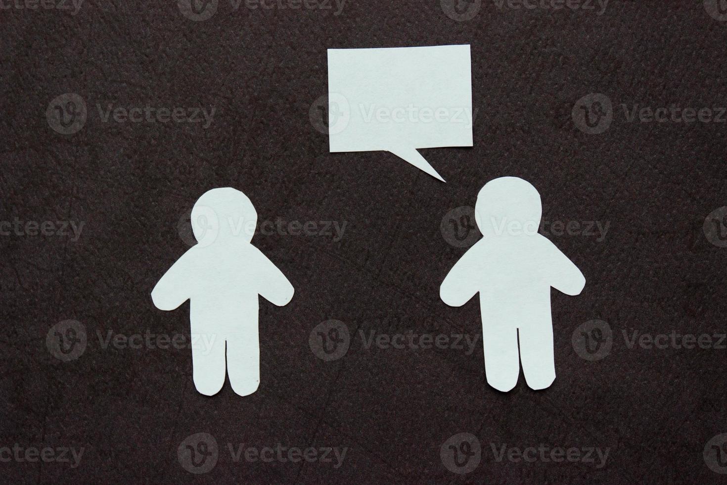 Silhouettes of two people cut from white paper on a black background. People stand opposite each other, one of them is speaking speech-bubble . Communication, leadership, partnership, teamwork, etc. photo