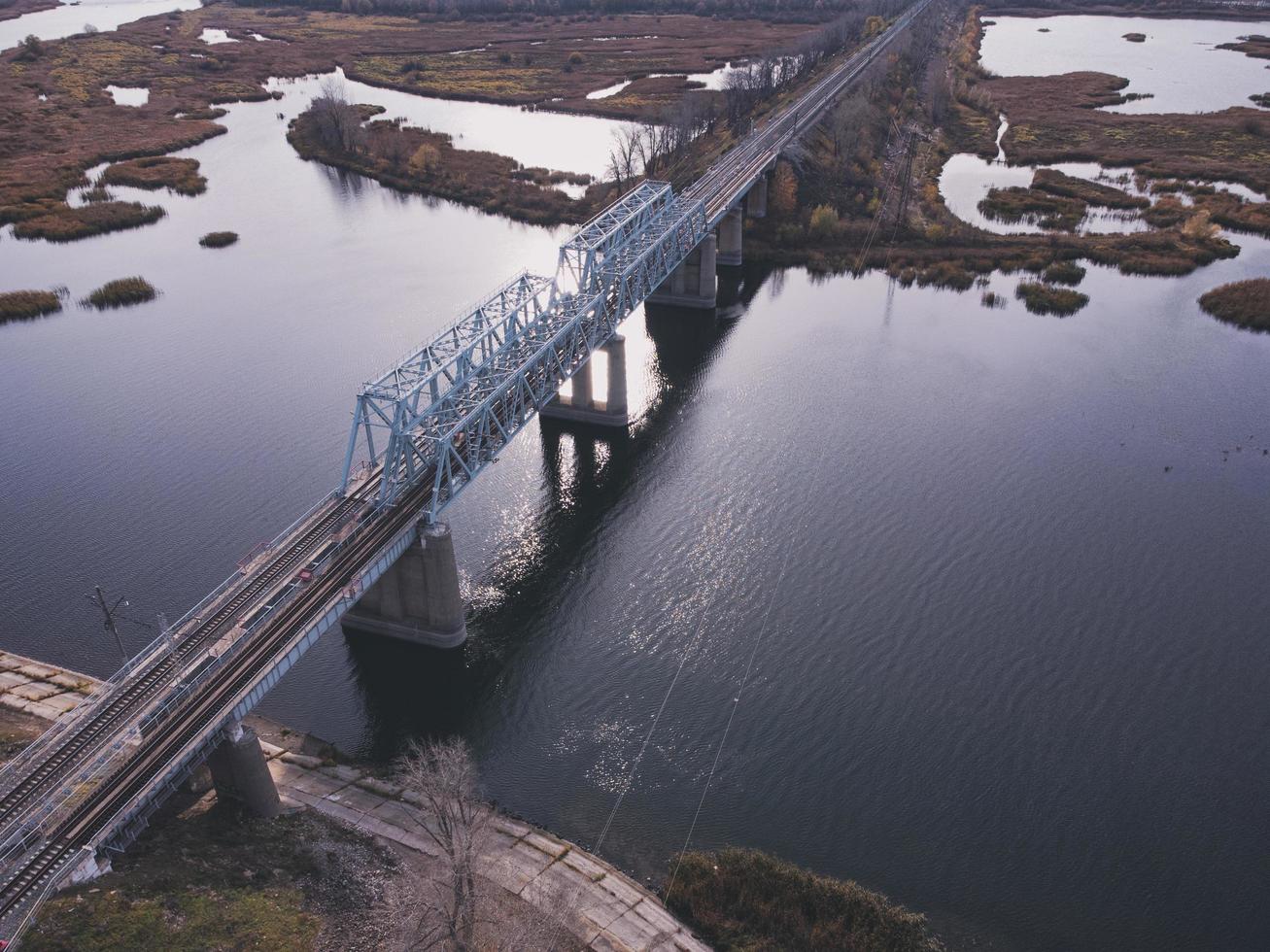 vista aérea de un cuerpo de agua con un puente ferroviario de metal sobre una base de hormigón. foto