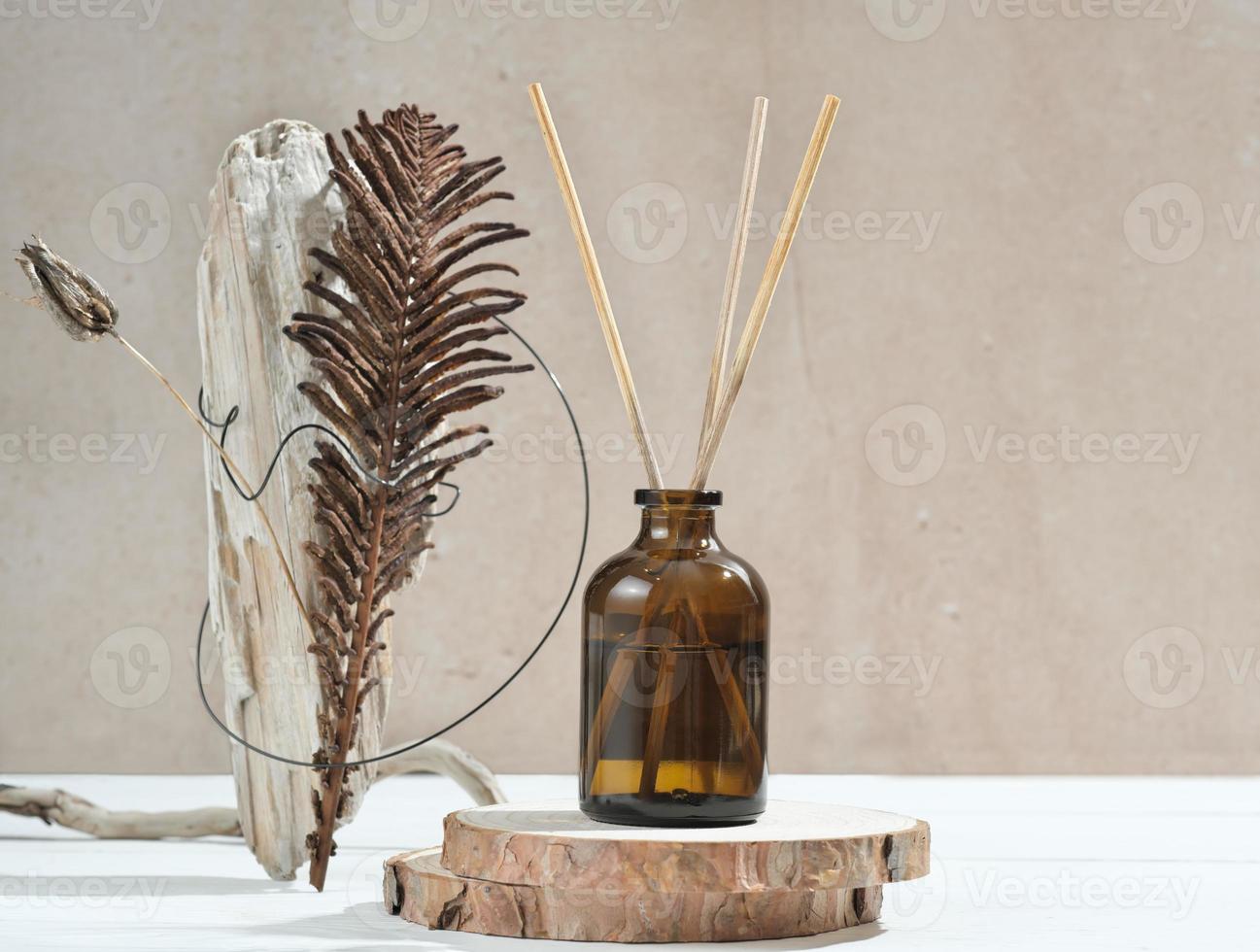 reed aroma diffuser on wooden podium with creative natural composition. woody fragrance for home, scents for cozy ambience in a house. photo