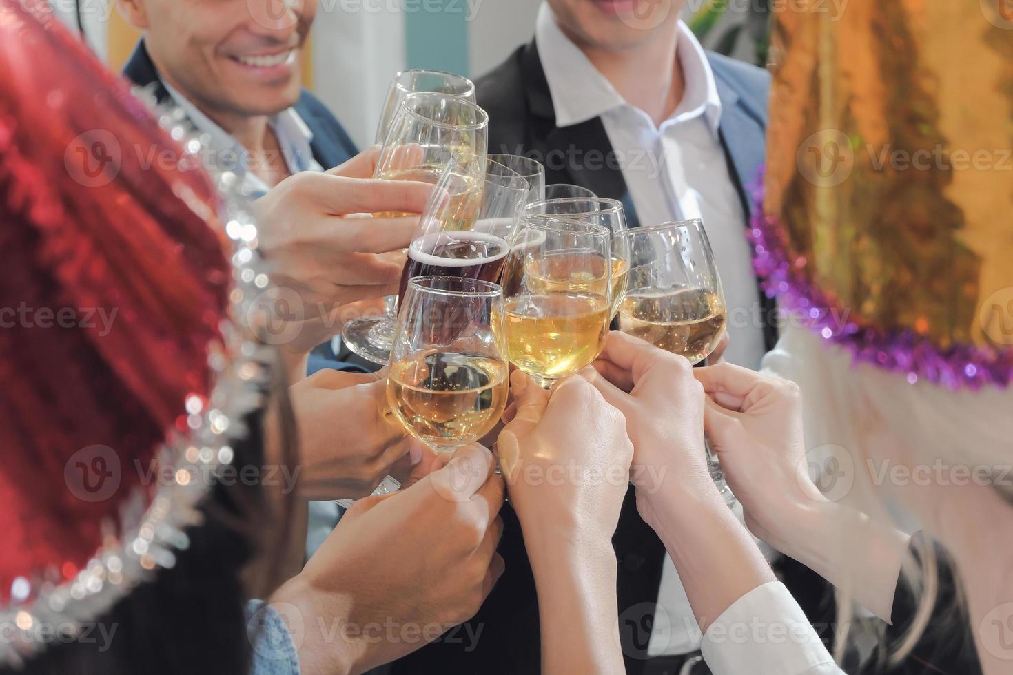 cerrar las manos de la gente de negocios tintineando copas de vino en la oficina fiesta de año nuevo con disfrutar de la sensación. foto