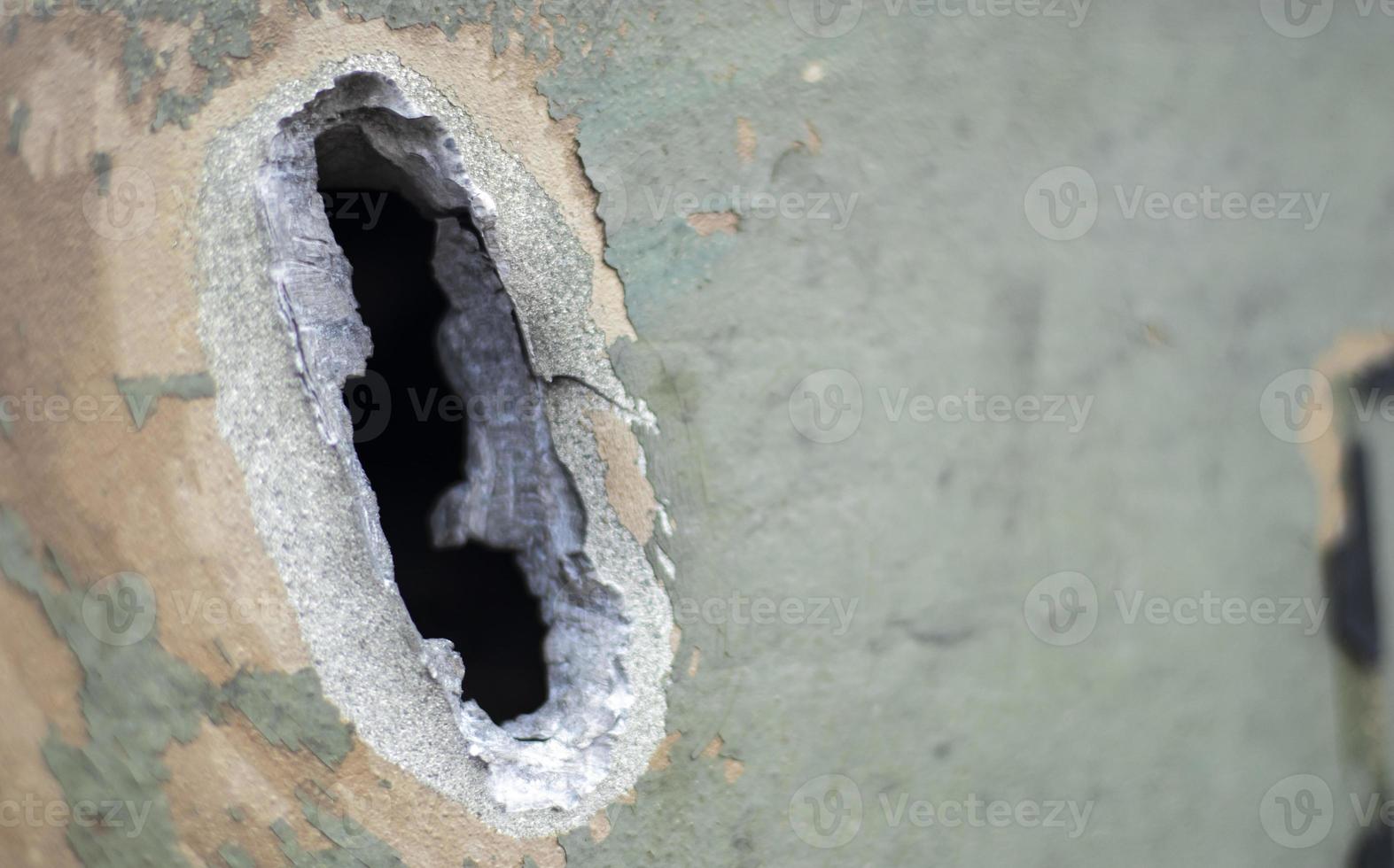 Hole or hole, armor deformation from a projectile close-up. Damaged armor of a Russian armored personnel carrier by shell fragments. War in Ukraine. Russian combat vehicle with holes in the armor. photo