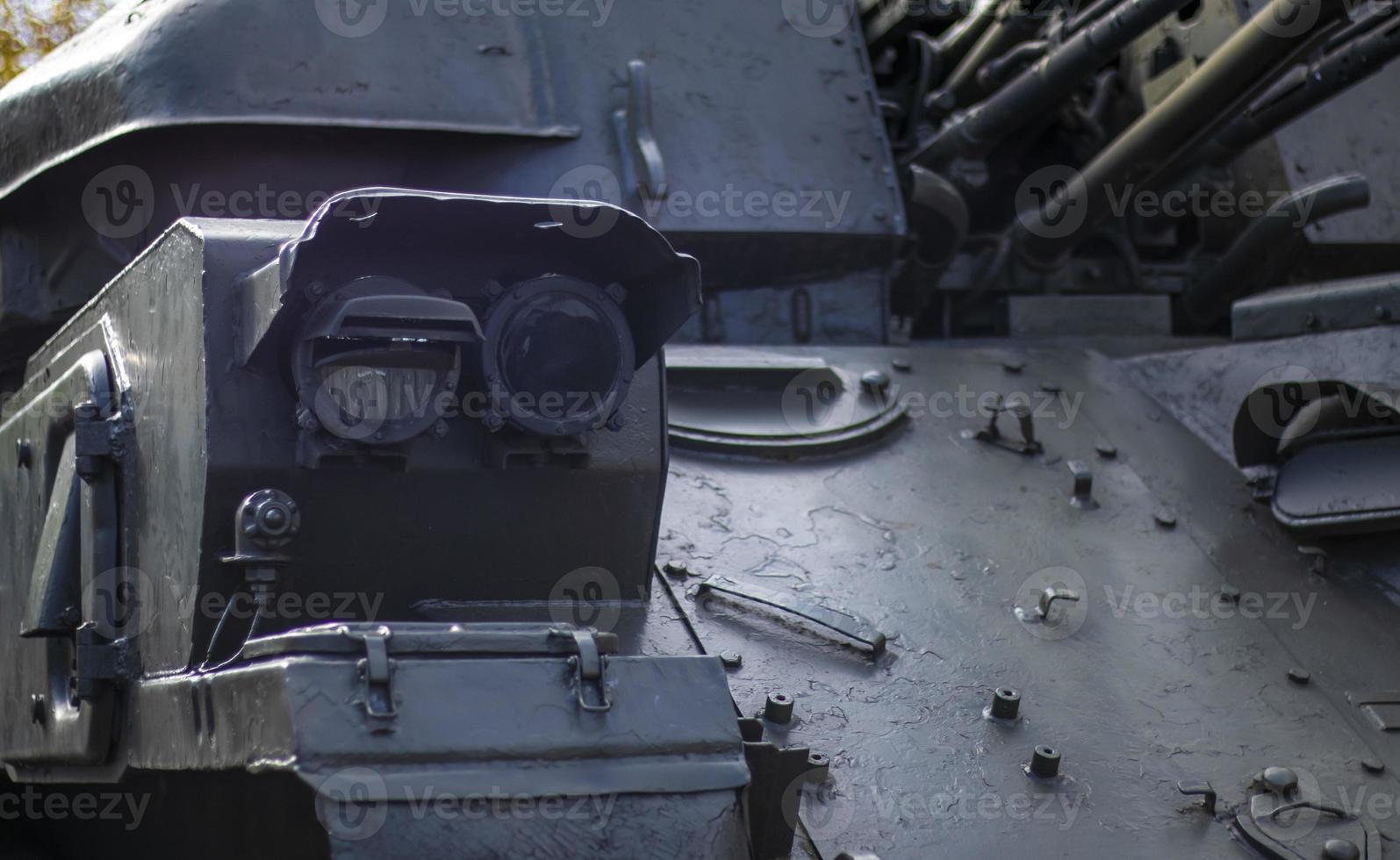 Front headlight with battle tank protection. Very bright searchlight on the tank turret, close-up. Armored infantry fighting vehicle. Fragment of an old armored personnel carrier, khaki headlight. photo