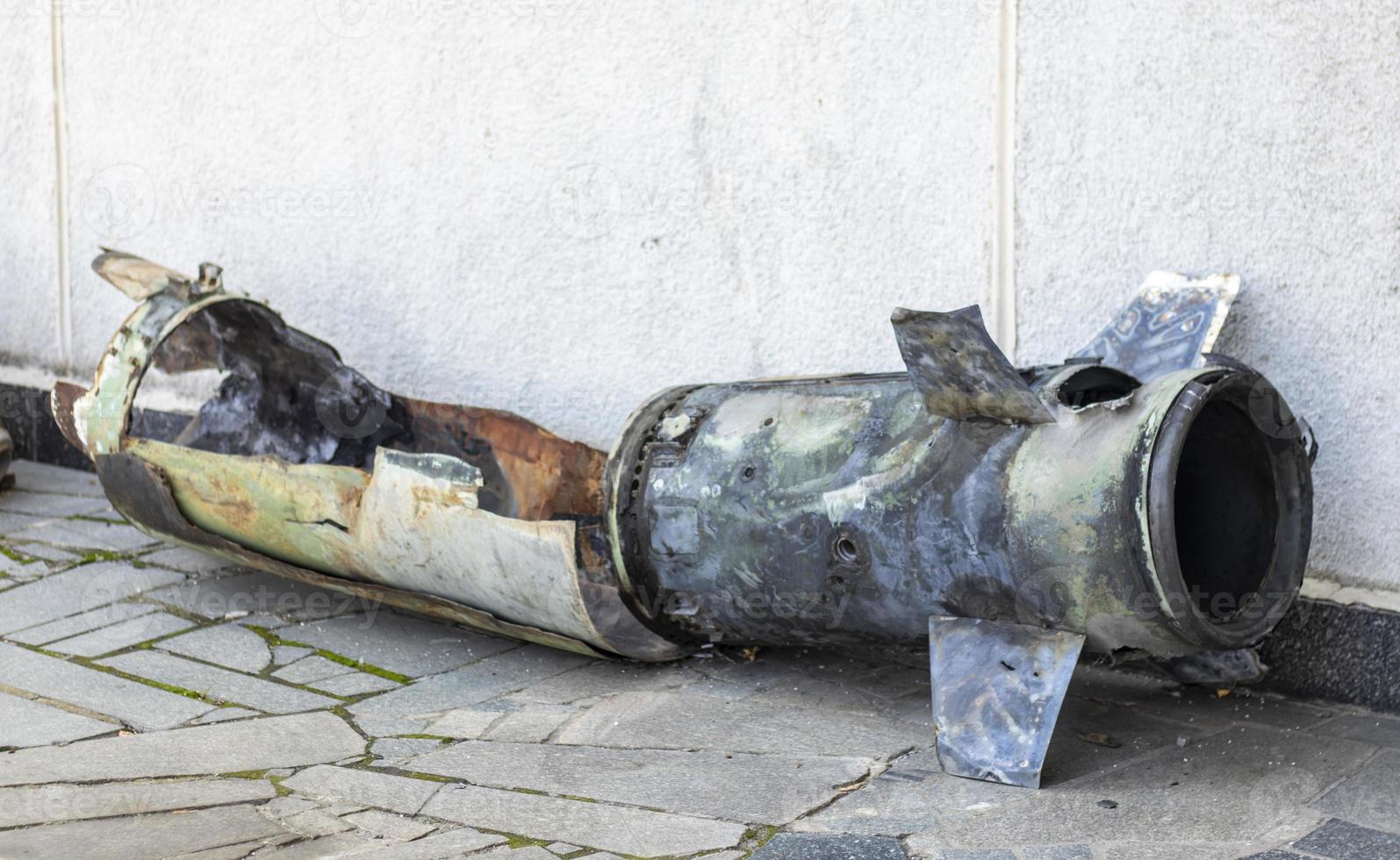 A metal fragment of a military rocket lies on the ground after the shelling of a civilian home. Rocket fire on the city and the horror of war. Ukraine war. The projectile is on the ground. photo