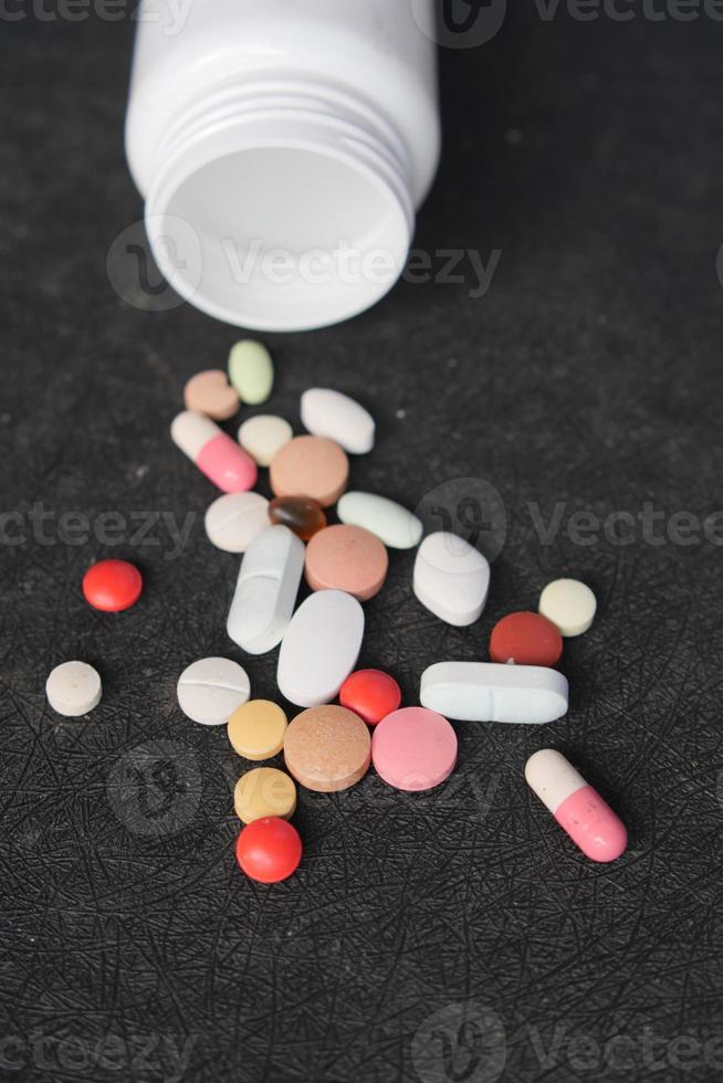 Cerca de muchas píldoras y cápsulas de colores sobre fondo negro foto