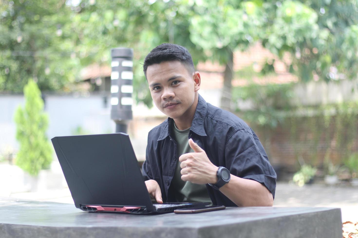 Atractivo joven asiático usando una laptop en un espacio de trabajo conjunto con cara feliz foto